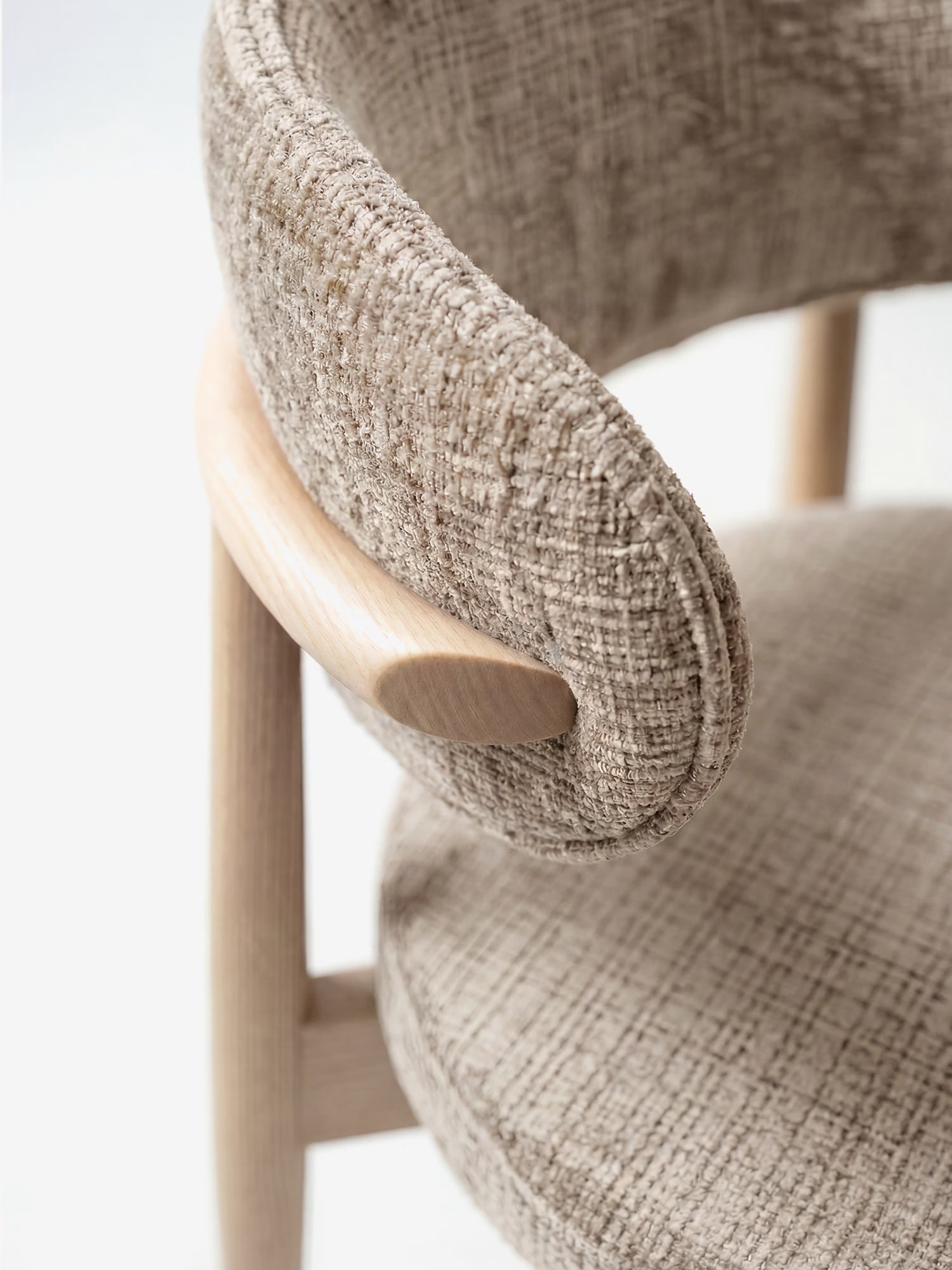Primo piano della sedia imbottita Dafne di Divani.Store, realizzata in ciniglia beige certificata OEKO-TEX®, caratterizzata da schienale e seduta curvi e da gambe leggere in rovere massello naturale, per un look minimalista ed elegante.