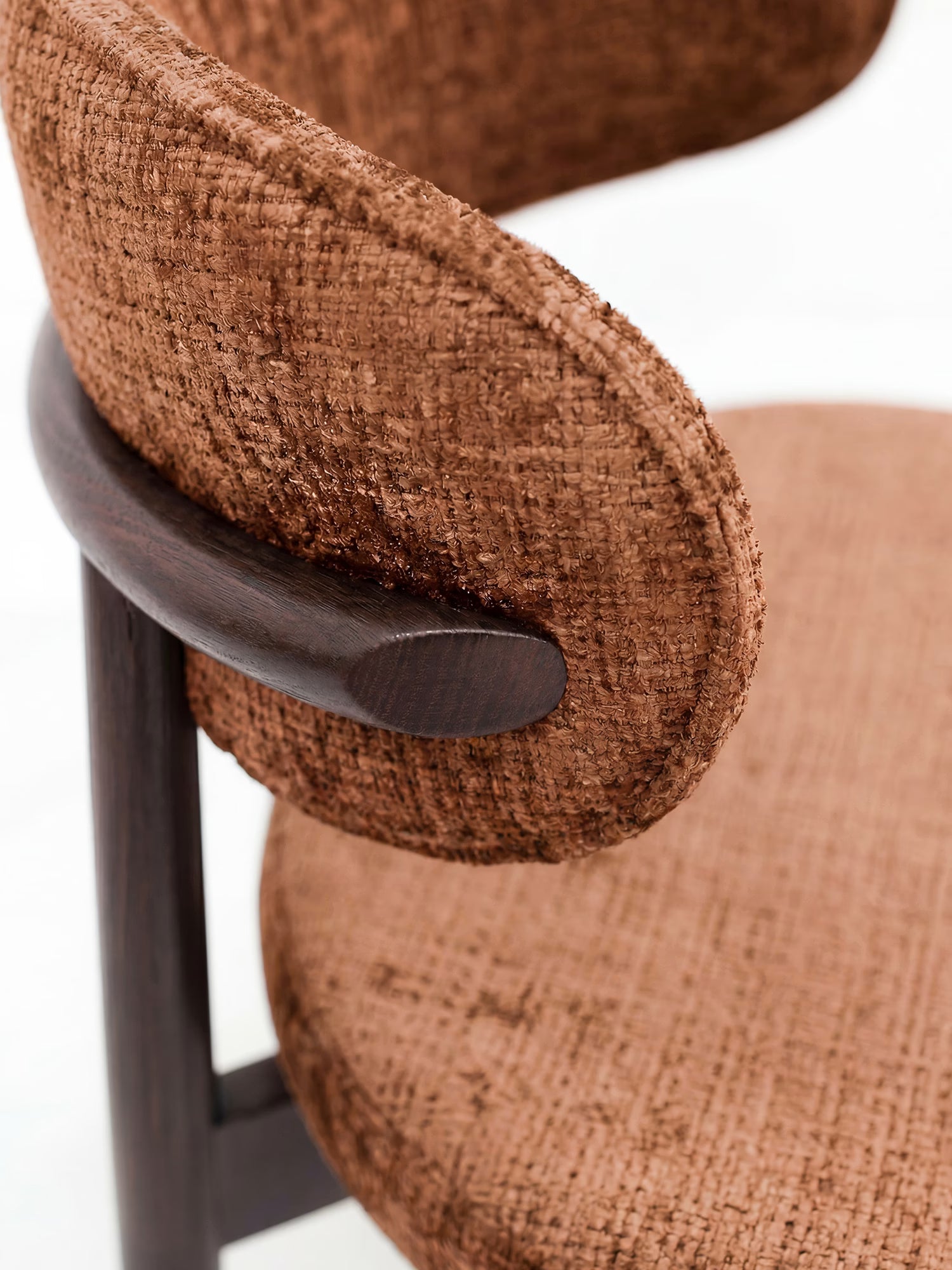 Primo piano della sedia imbottita Dafne di Divani.Store, realizzata in legno massello wengé e ciniglia marrone certificata OEKO-TEX®. Lo schienale curvo, la seduta arrotondata e le cuciture curate ne accentuano lo stile contemporaneo.