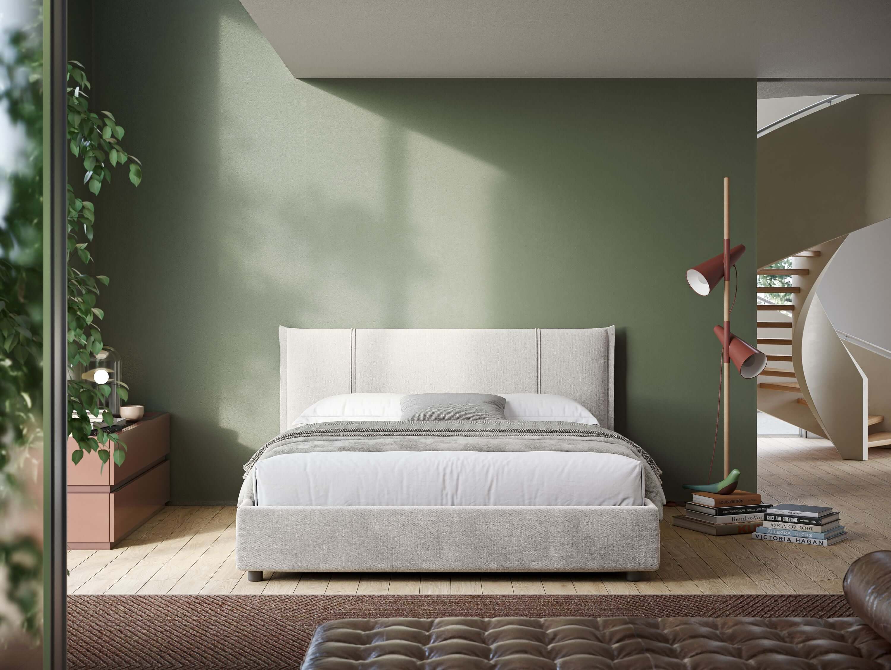Una camera da letto moderna presenta il letto Alicia imbottito con vano contenitore in tessuto impermeabile T14 panna di Letti.store contro una parete verde, con un comodino marrone e una pianta a sinistra, una lampada da terra rossa a destra, libri sul pavimento, luce solare e una scala a chiocciola alle spalle.