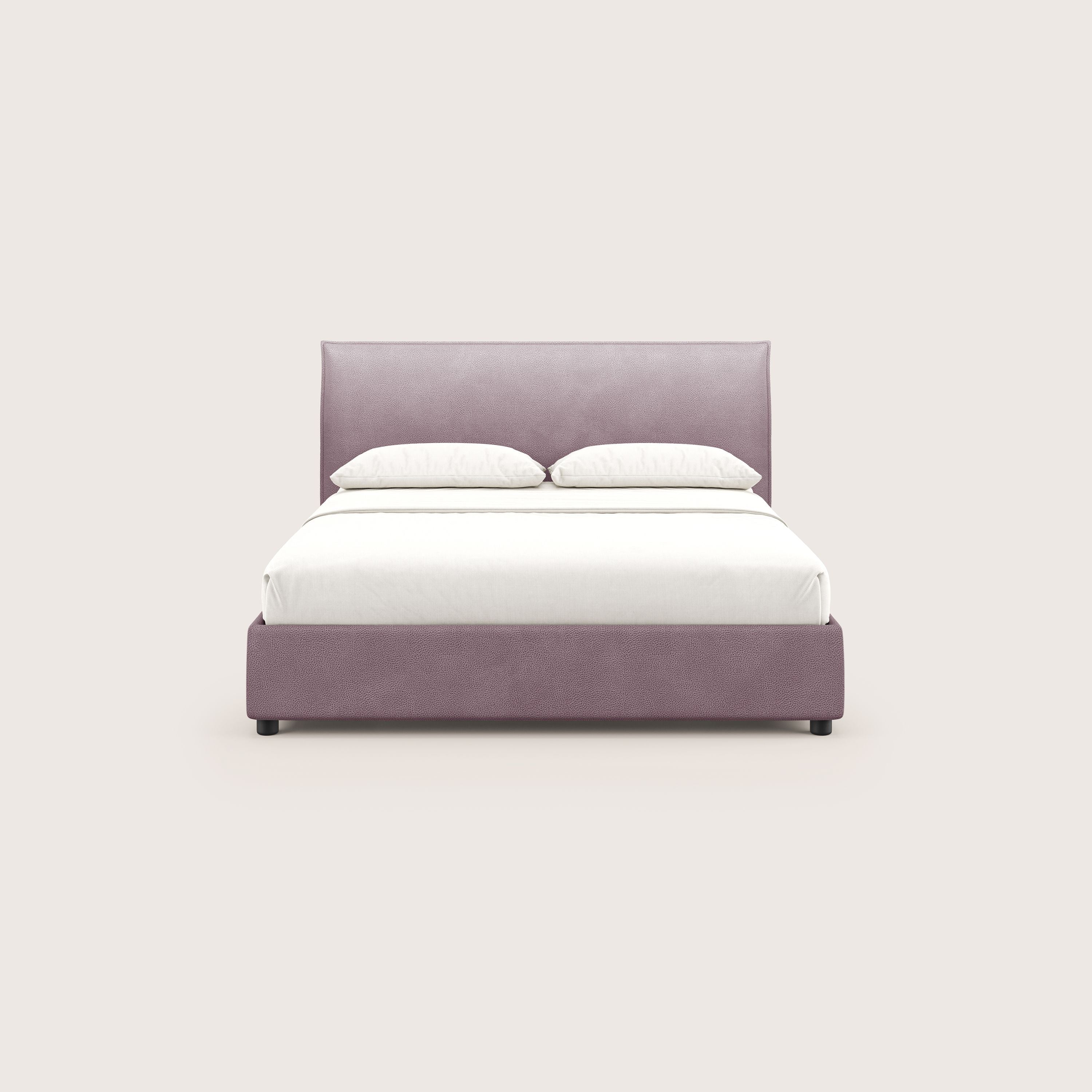 Il letto contenitore Nina di Letti.store, un letto minimal in microfibra rosa con rivestimento antimacchia effetto pelle, è caratterizzato da un'alta testata imbottita e da una biancheria da letto bianca con due cuscini, mostrata frontalmente su uno sfondo beige chiaro.