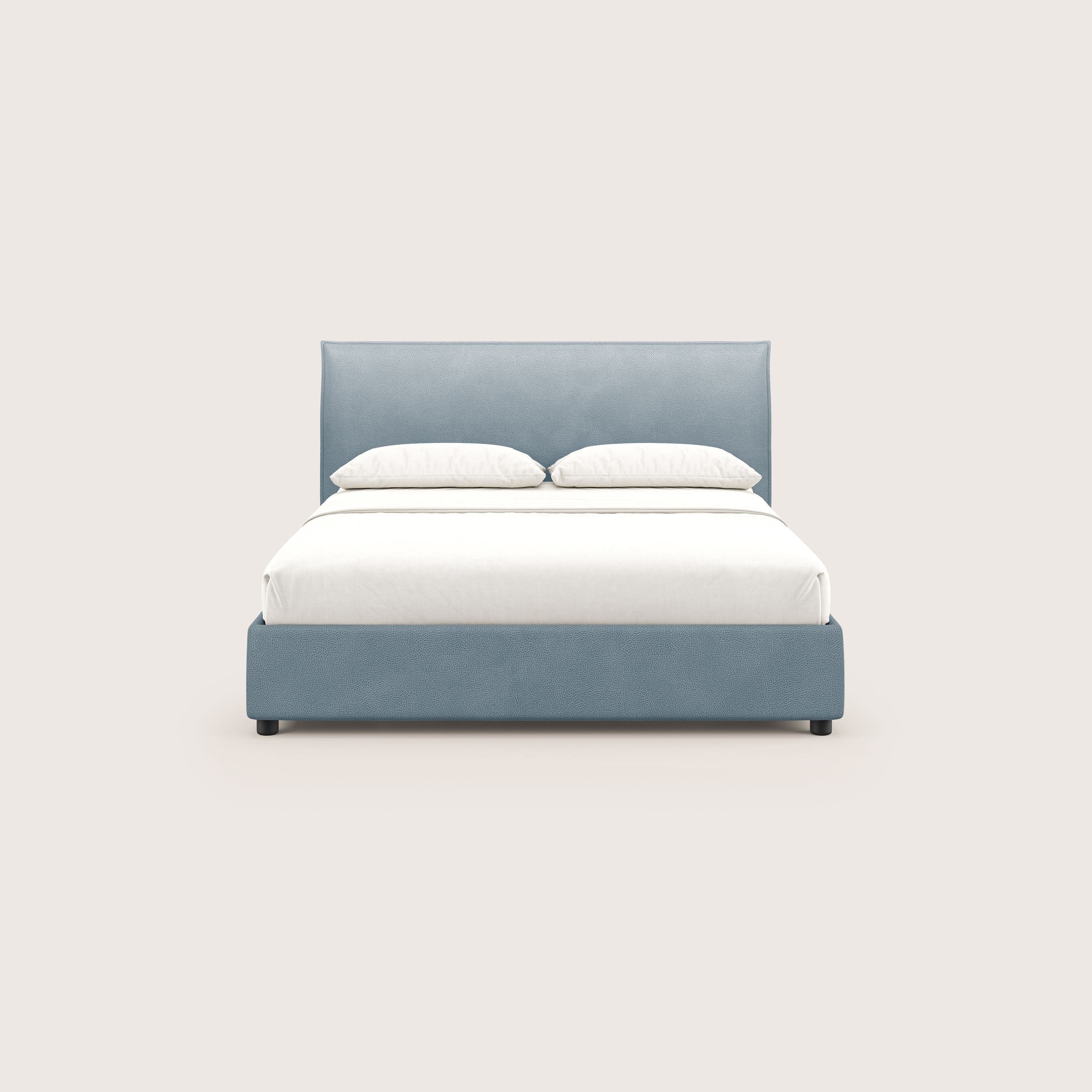 Il letto contenitore Nina di Letti.store è caratterizzato da un design minimale con rivestimento in microfibra smacchiabile carta da zucchero, biancheria da letto bianca e due cuscini bianchi, mostrati frontalmente e centrati su uno sfondo beige chiaro.