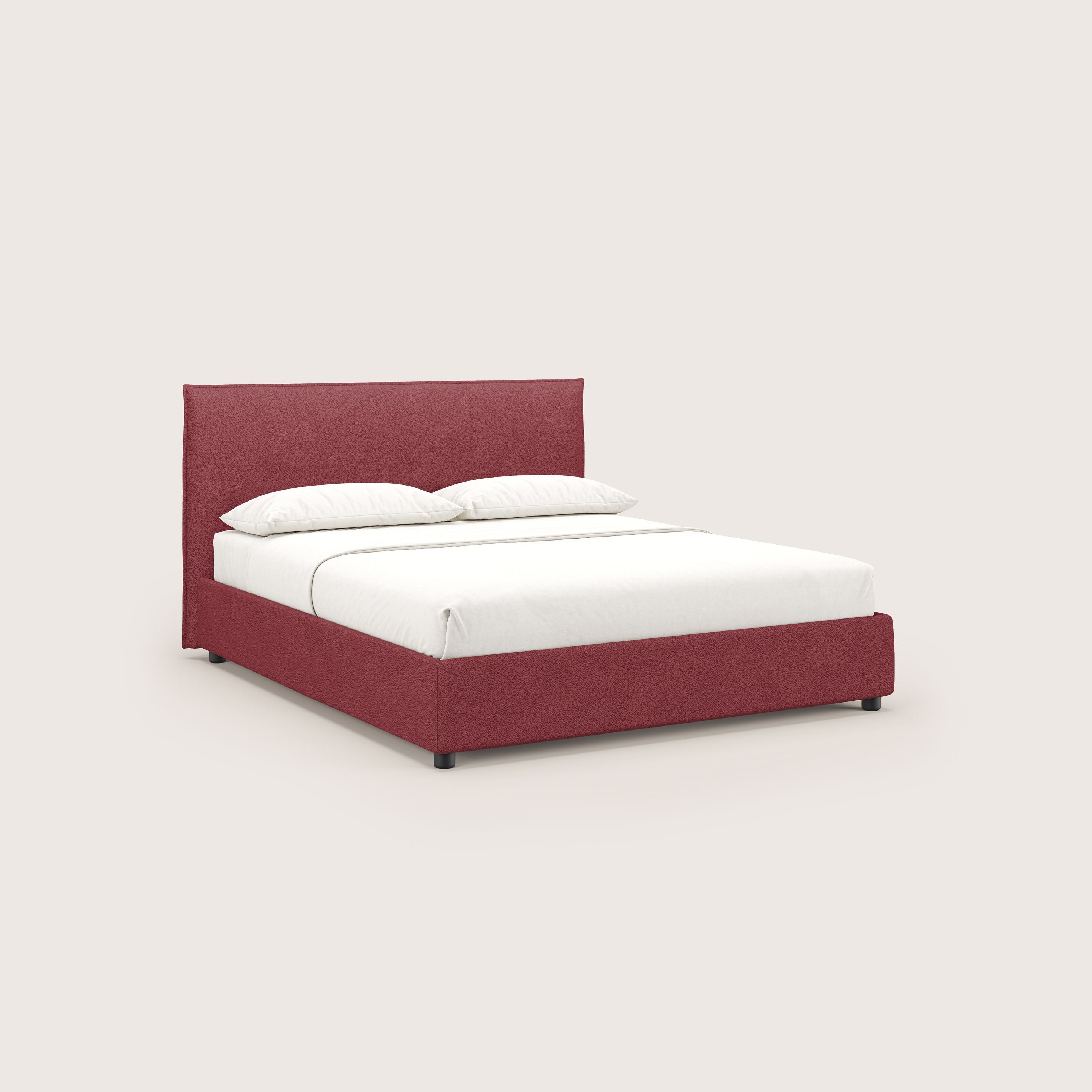 Il letto contenitore Nina di Letti.store è caratterizzato da un design minimale in microfibra rossa effetto pelle antimacchia, con una semplice struttura e testata rettangolare, biancheria da letto bianca e due cuscini su uno sfondo beige chiaro.