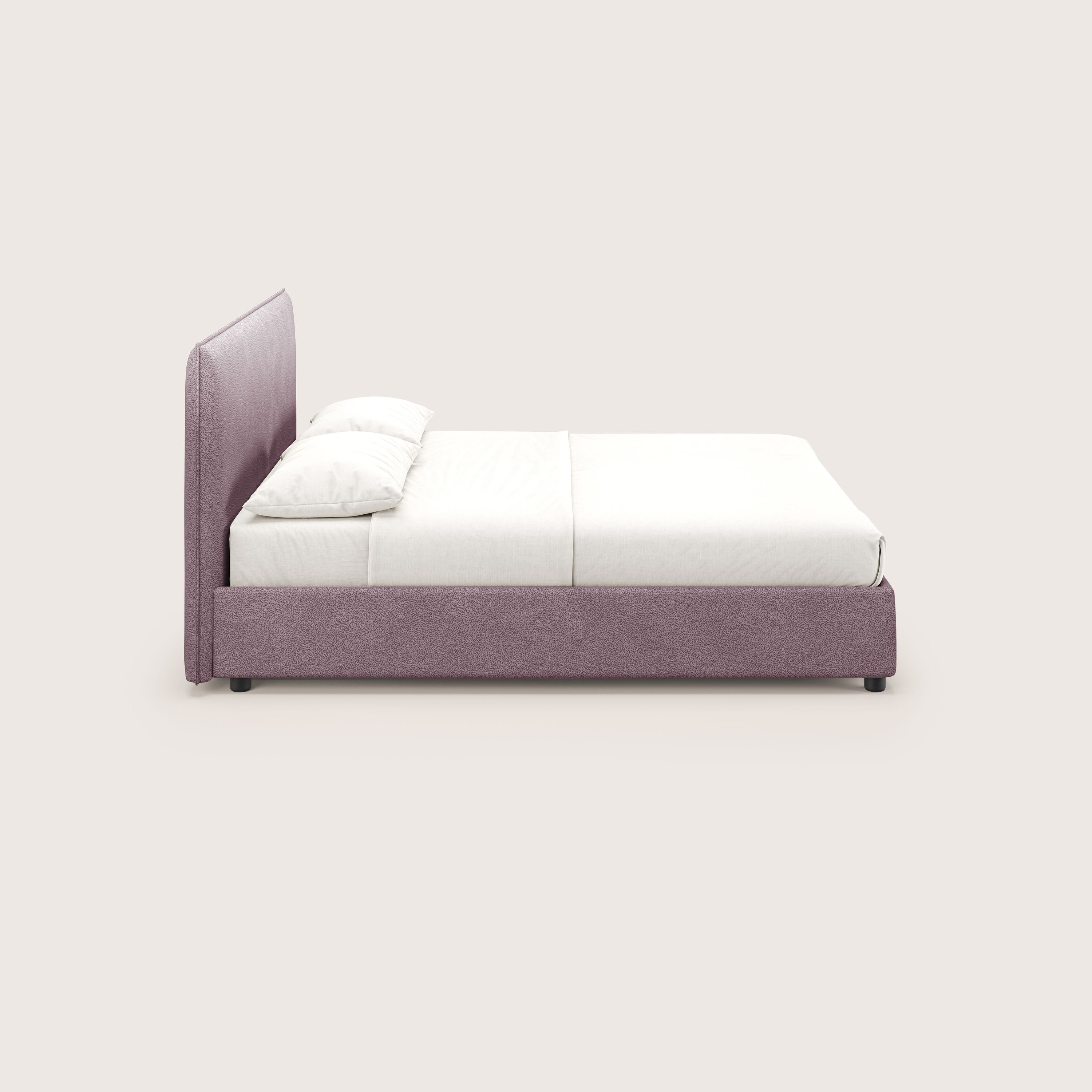 Il letto contenitore Nina di Letti.store è caratterizzato da un design minimale in microfibra rosa facile da pulire, con testiera e struttura imbottite, lenzuola bianche, due cuscini bianchi e una coperta bianca, raffigurati di profilo su uno sfondo beige chiaro.