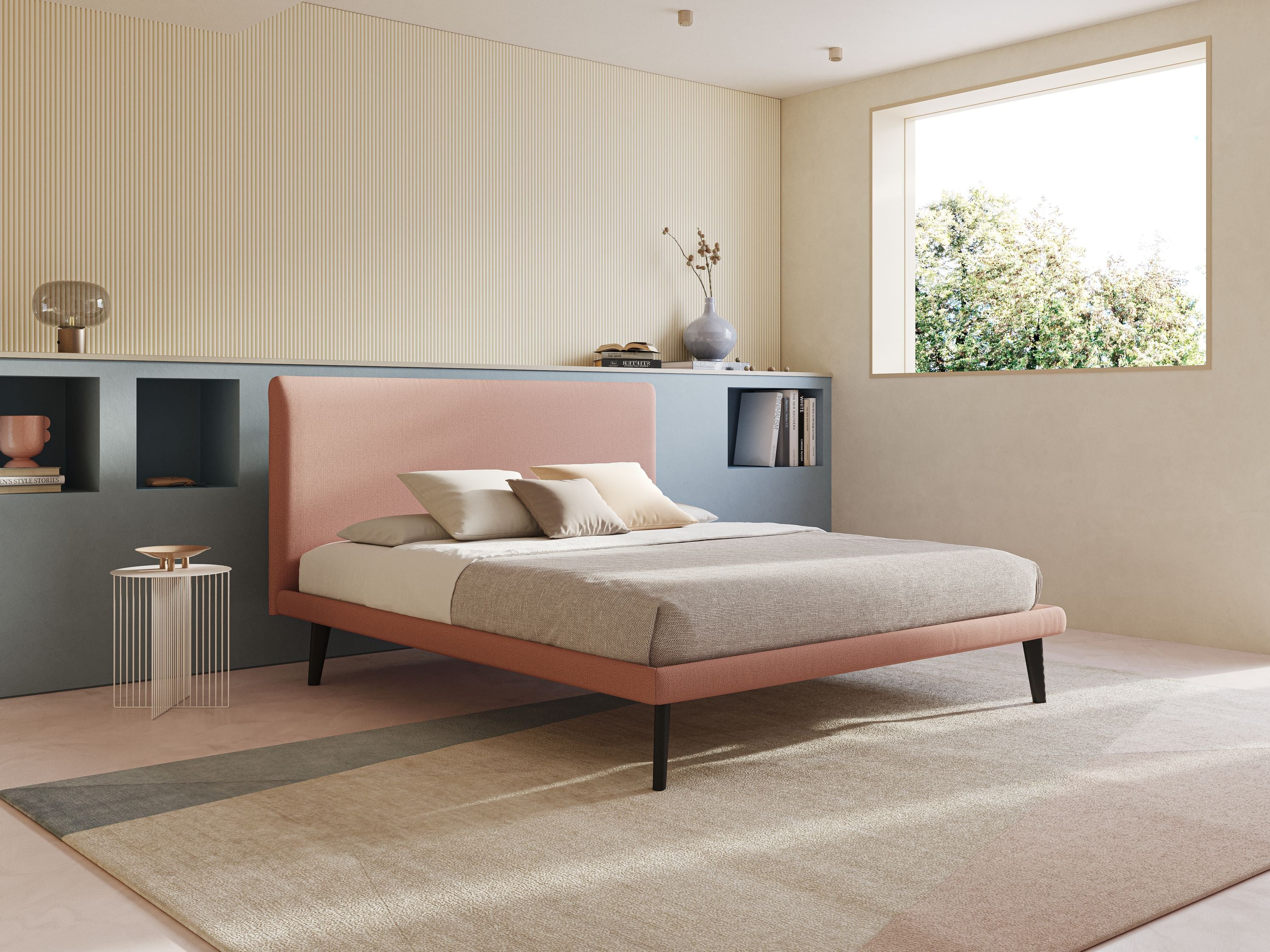 Una camera da letto moderna con il letto minimal scandinavo Noel di Letti.store in salmone T19 con gambe in mogano e rete ortopedica a doghe, abbinato a biancheria da letto grigia, cuscini beige, una mensola blu e luce naturale per un look tranquillo e minimalista.