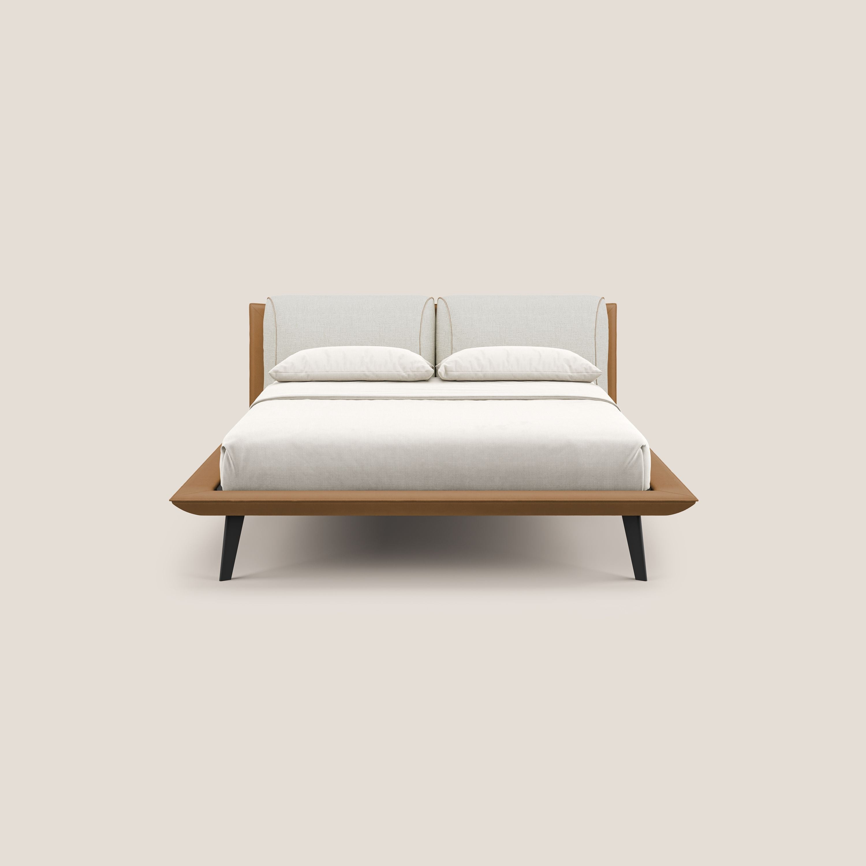 Il letto di design Petra di Letti.store è caratterizzato da un tessuto bicolore impermeabile T11 e T06 cuoio-panna, cuscini in piuma, profilo basso, gambe in mogano e un'ordinata rete a doghe ortopediche bianca su sfondo beige chiaro.