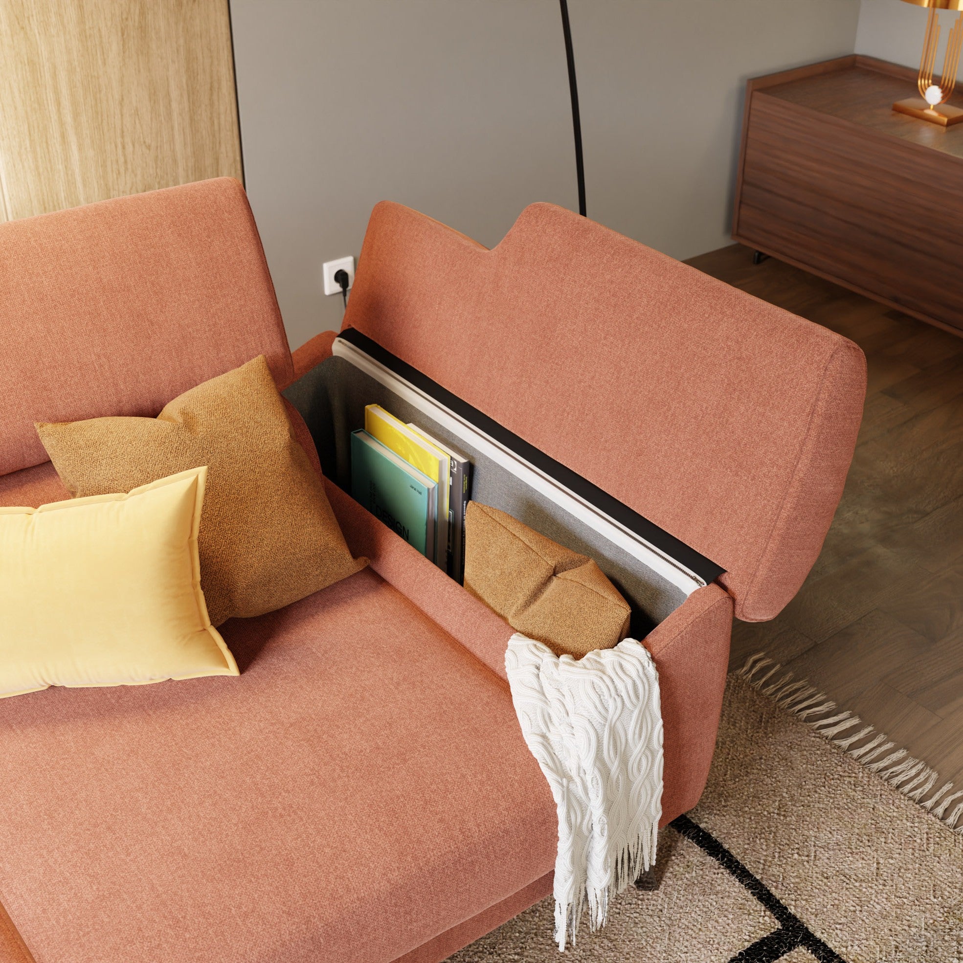 Il divano Donatello di Divani.Store è caratterizzato da 3 sedute allungabili, braccioli contenitore, poggiatesta reclinabili in tessuto smacchiabile T23 pesca, con contenitori nascosti per libri, una pochette gialla e una coperta bianca. Cuscini e tappeto completano il look.