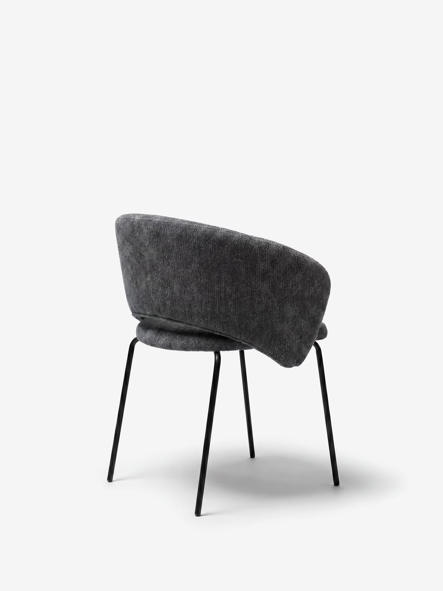 La sedia imbottita Fosca di Divani.Store presenta una seduta e uno schienale curvi in tessuto grigio scuro certificato OEKO-TEX® con braccioli, oltre a sottili gambe in metallo nero; nella foto è raffigurata inclinata verso sinistra su uno sfondo bianco a tinta unita, per un look moderno.