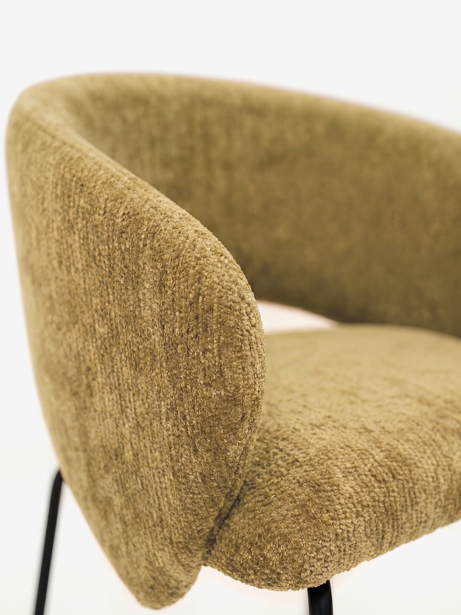 Primo piano della sedia imbottita Fosca di Divani.Store, caratterizzata da braccioli, morbido tessuto certificato OEKO-TEX® color verde oliva, schienale e seduta arrotondati e sottili gambe in metallo nero che le conferiscono un look moderno.