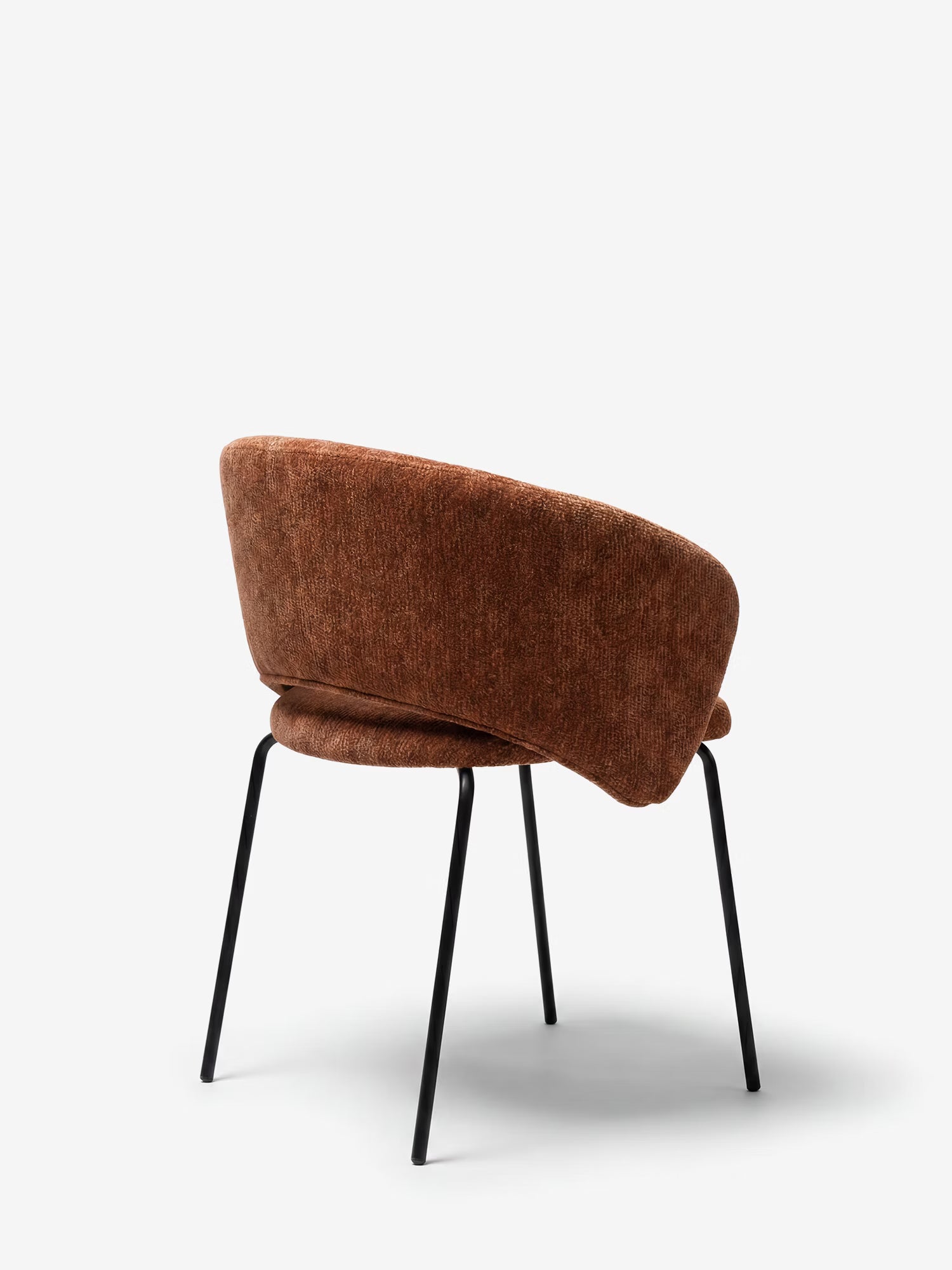La sedia imbottita Fosca di Divani.Store presenta uno schienale e una seduta curvi in tessuto color ruggine, certificati OEKO-TEX®, con eleganti gambe e braccioli in metallo nero; è raffigurata su uno sfondo bianco a tinta unita, in una posa che ne mostra lo schienale e il profilo laterale.