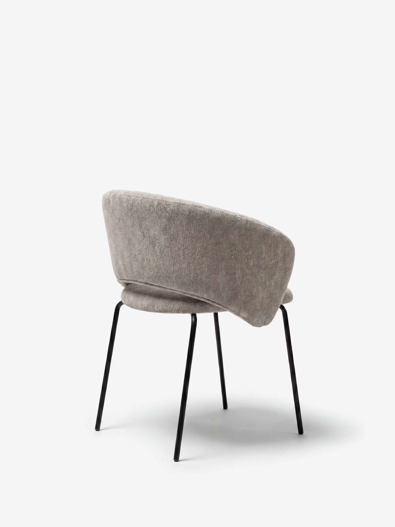 La sedia imbottita Fosca di Divani.Store è caratterizzata da un morbido tessuto certificato OEKO-TEX®, da un moderno schienale curvo con braccioli e da sottili gambe in metallo nero, il tutto presentato in uno stile minimalista su uno sfondo bianco a tinta unita.