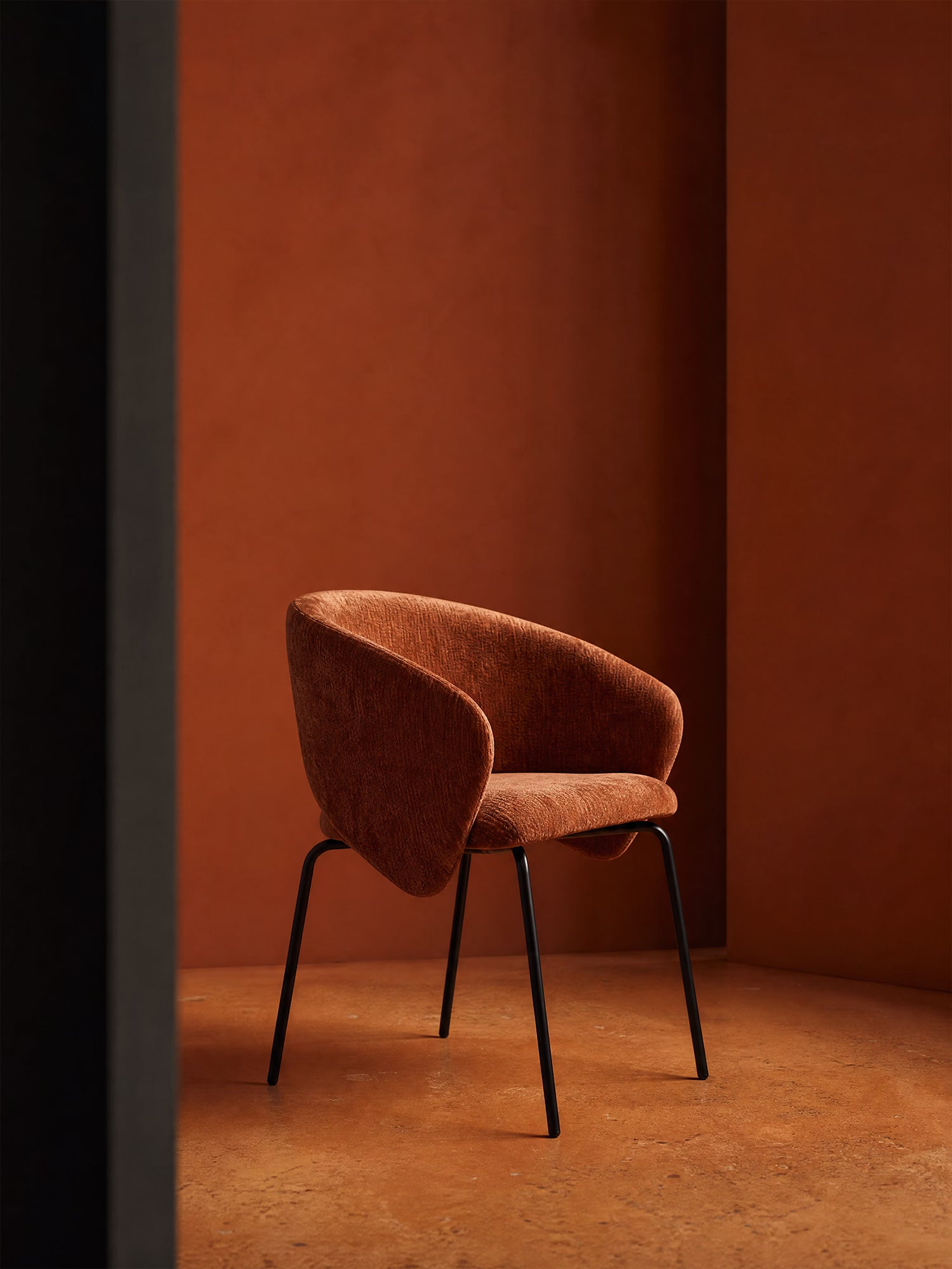 La poltrona imbottita con braccioli Fosca di Divani.Store è realizzata con tessuto color ruggine certificato OEKO-TEX® e sottili gambe in metallo nero; il suo design moderno esalta l'atmosfera calda e minimalista di qualsiasi ambiente.