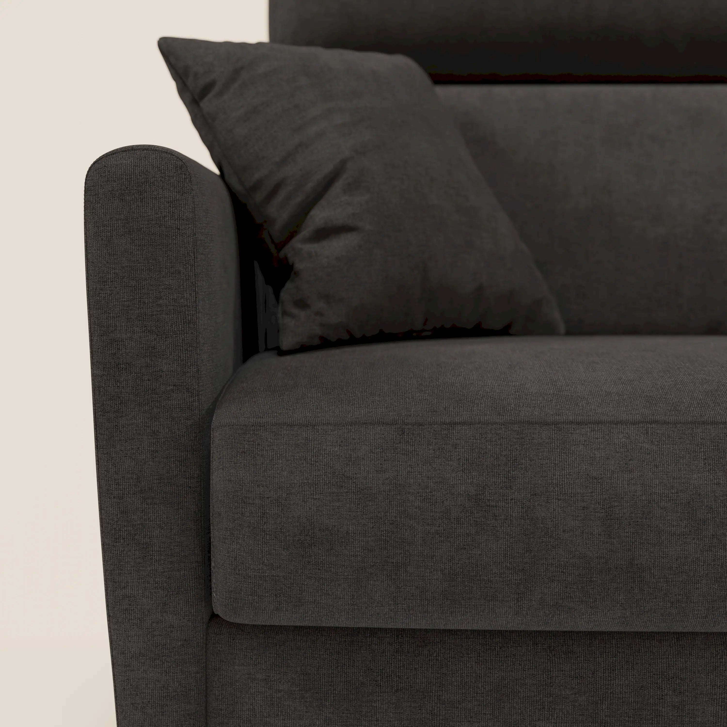 Primo piano del divano letto angolare Francy di Divani.Store in tessuto smacchiabile T17 antracite, che mostra il bracciolo, la seduta, i poggiatesta reclinabili e il design in stile nordico con cuscino coordinato su uno sfondo chiaro.