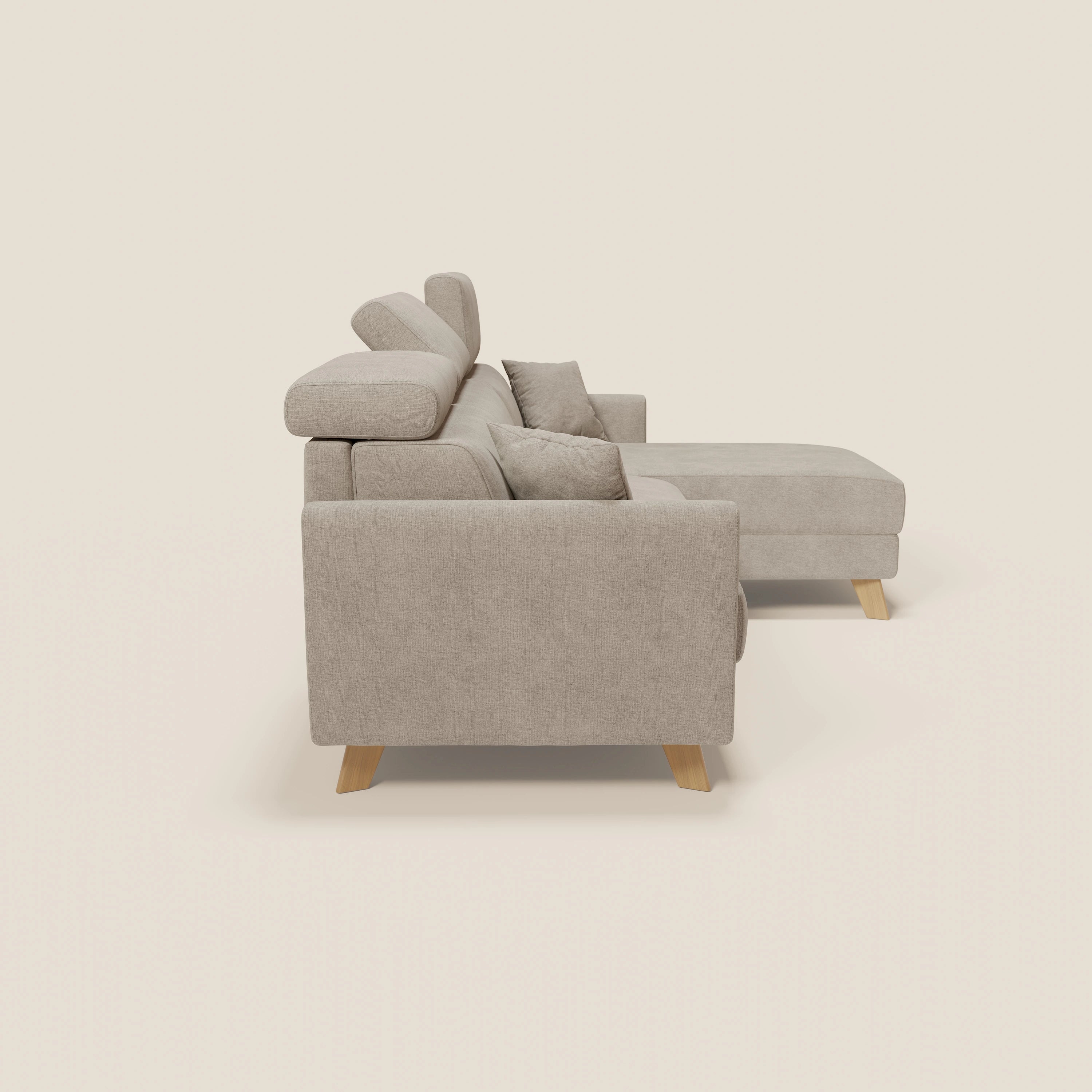 Vista laterale del divano letto angolare sfoderabile Francy di Divani.Store in tessuto smacchiabile T17 beige, caratterizzato da chaise longue destra, poggiatesta reclinabili e gambe corte in legno su sfondo bianco sporco.