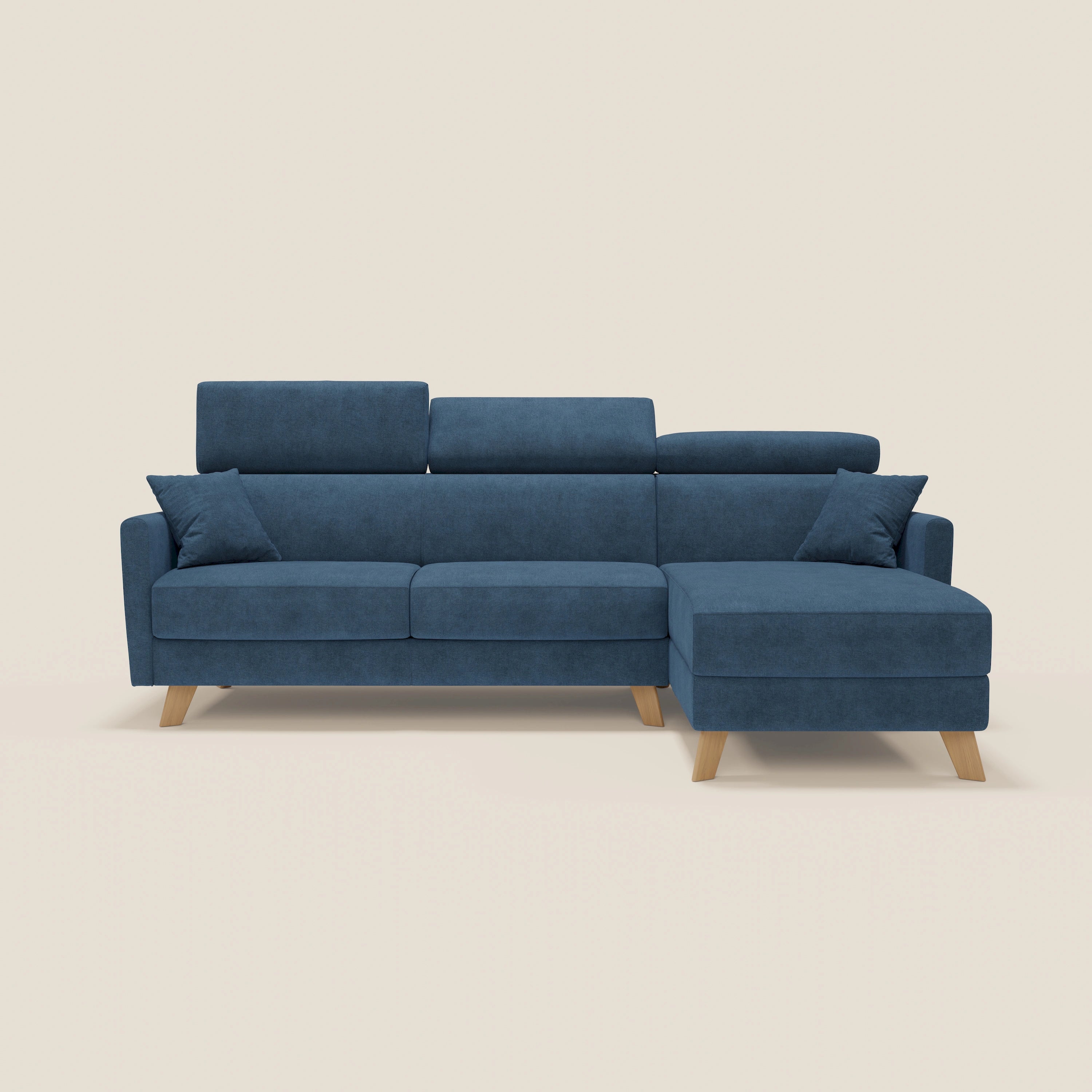 Il divano letto angolare sfoderabile Francy di Divani.Store è caratterizzato da un tessuto antimacchia blu T17, poggiatesta reclinabili, chaise longue contenitore a destra, gambe in legno e due cuscini coordinati, su uno sfondo beige chiaro.