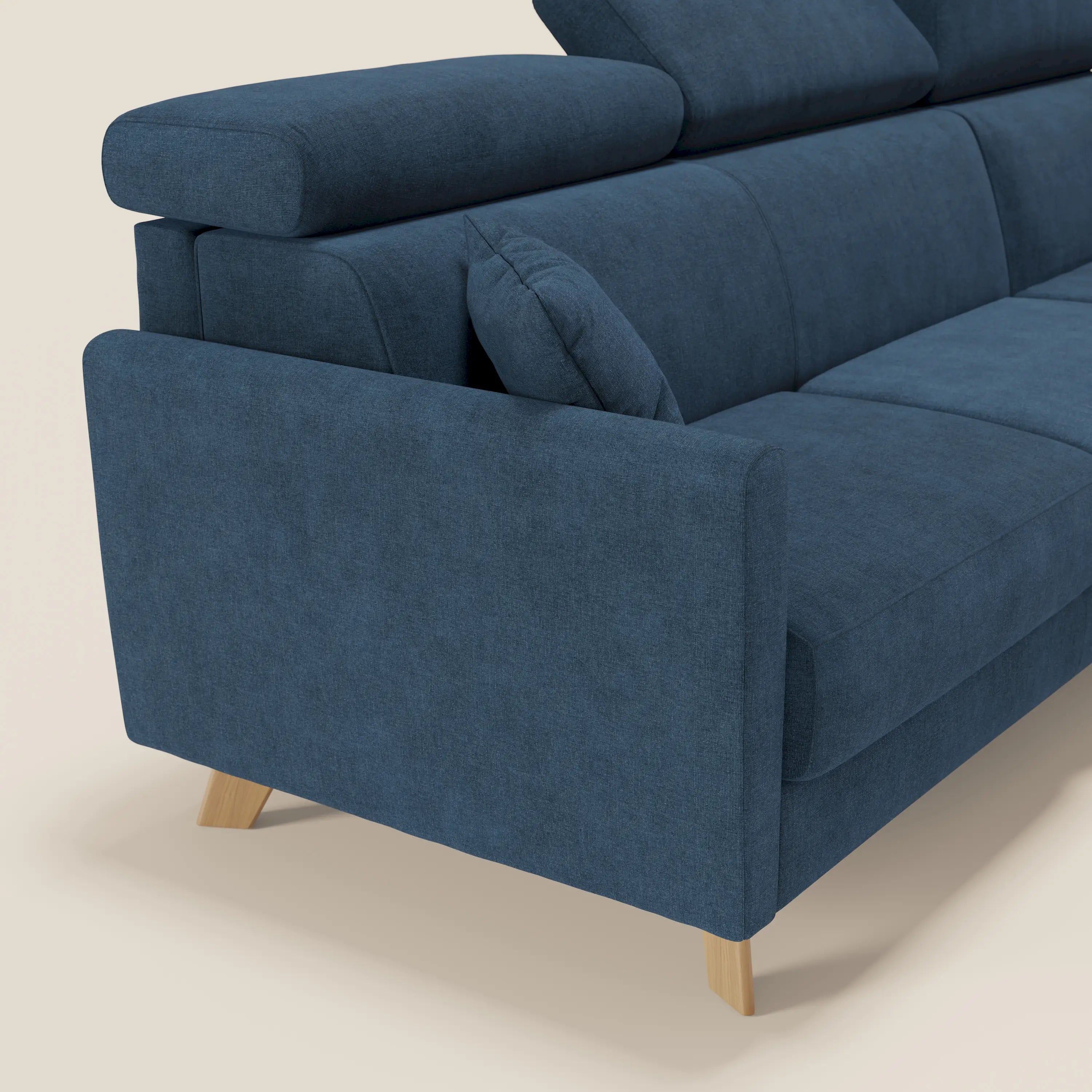 Il divano letto angolare sfoderabile Francy di Divani.Store in tessuto blu T17, facile da pulire, è dotato di una poltrona contenitore, di un poggiatesta reclinabile e di ampi braccioli. Posizionato ad angolo, spicca su uno sfondo chiaro.