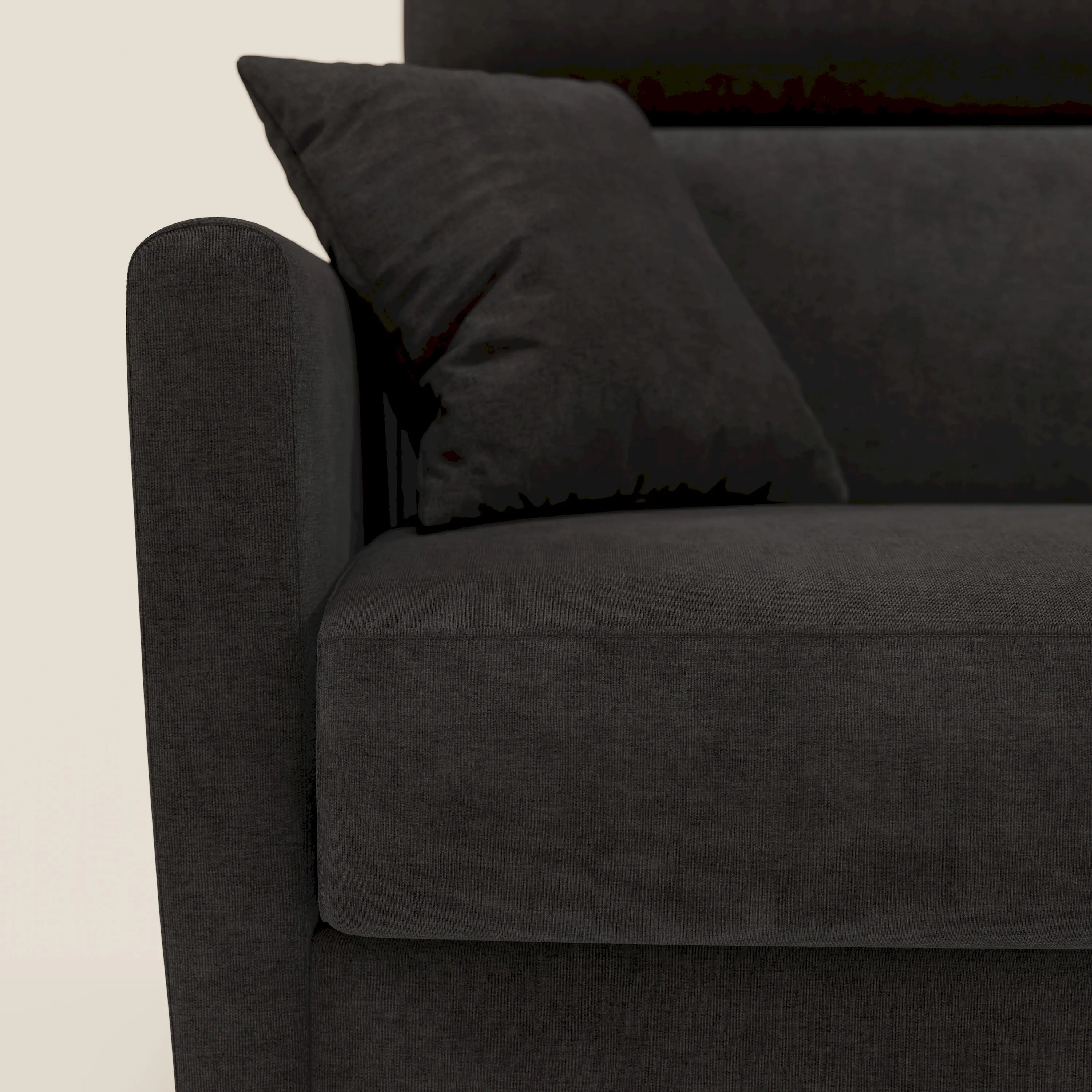 Primo piano del divano letto angolare sfoderabile Francy di Divani.Store in T17 nero, con penisola contenitore, poggiatesta reclinabili, braccioli semplici e arrotondati e cuscini in tessuto. La parete bianca evidenzia il suo design minimalista in stile nordico.