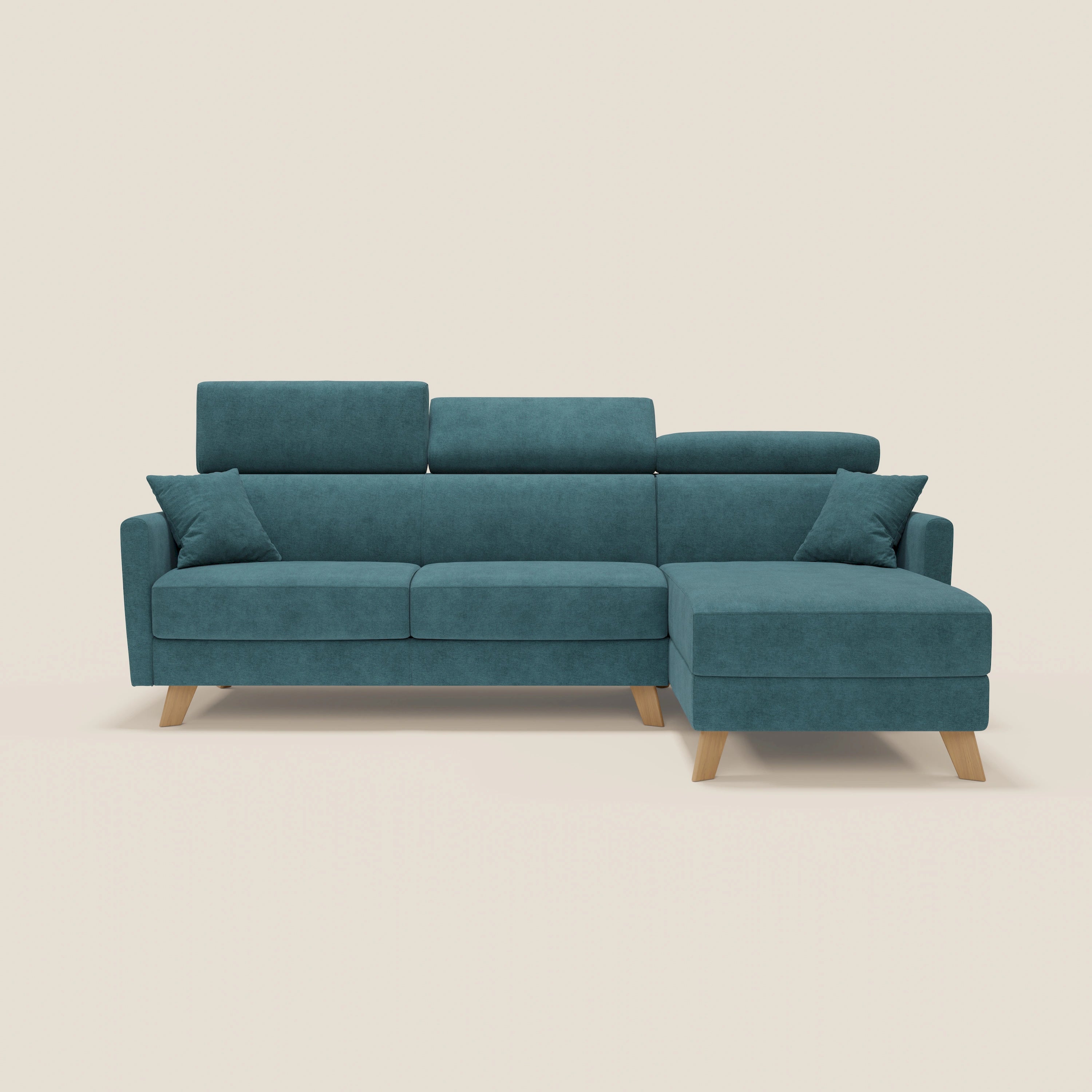 Il divano letto angolare sfoderabile Francy di Divani.Store in T17 petrolio è caratterizzato da una chaise longue destra, due cuscini, poggiatesta reclinabili e gambe angolari in legno chiaro per un tocco nordico, su uno sfondo bianco sporco.