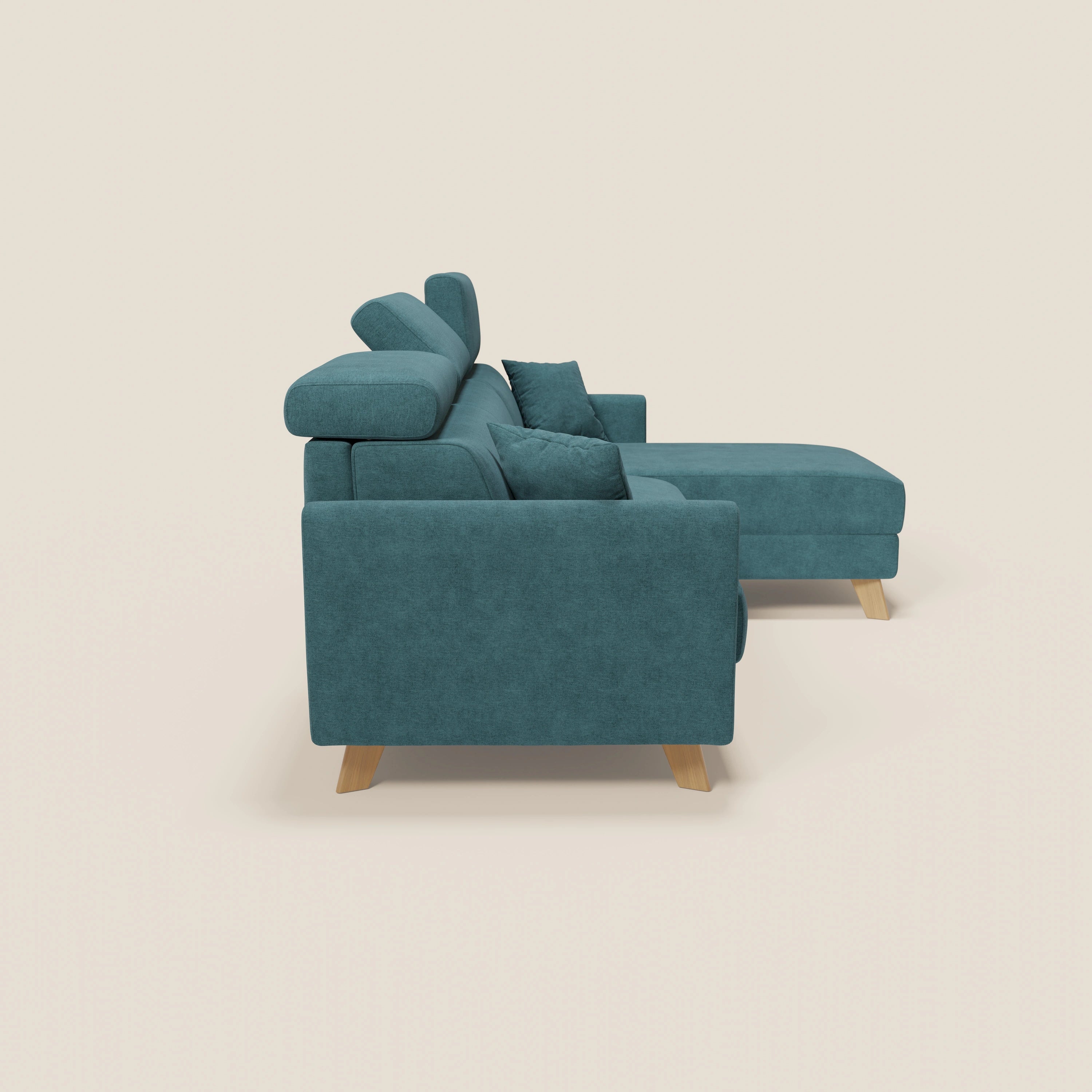 Il divano letto angolare sfoderabile Francy di Divani.Store in T17 petrolio è caratterizzato da poggiatesta reclinabili, chaise longue contenitore, gambe in legno e due cuscini coordinati, presentati affiancati su sfondo beige.