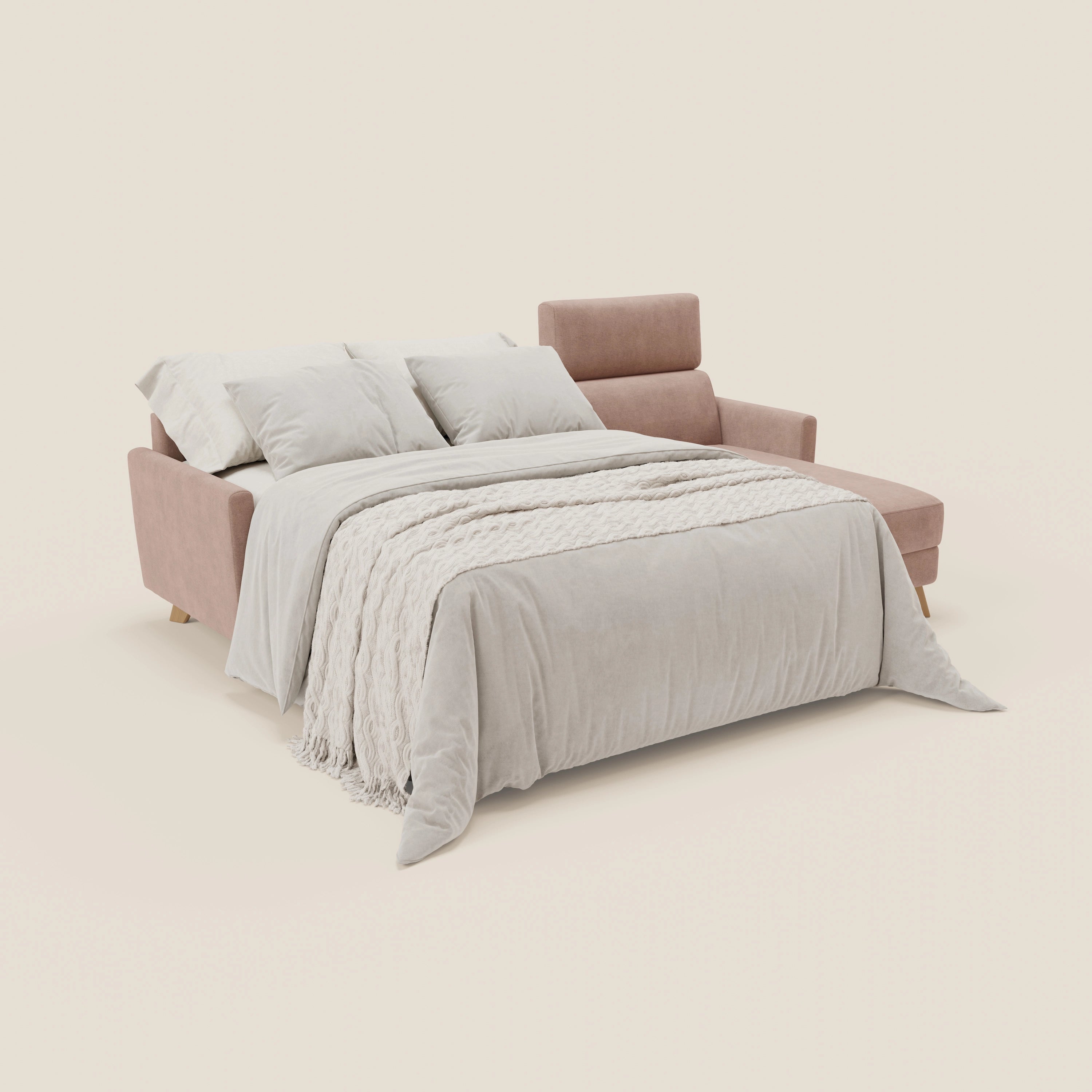 Il divano letto angolare sfoderabile Francy di Divani.Store in tessuto antimacchia rosa T17 è presentato come letto allungato, con chaise lounge, penisola contenitore e poggiatesta regolabili, abbinato a biancheria da letto neutra su uno sfondo bianco sporco.