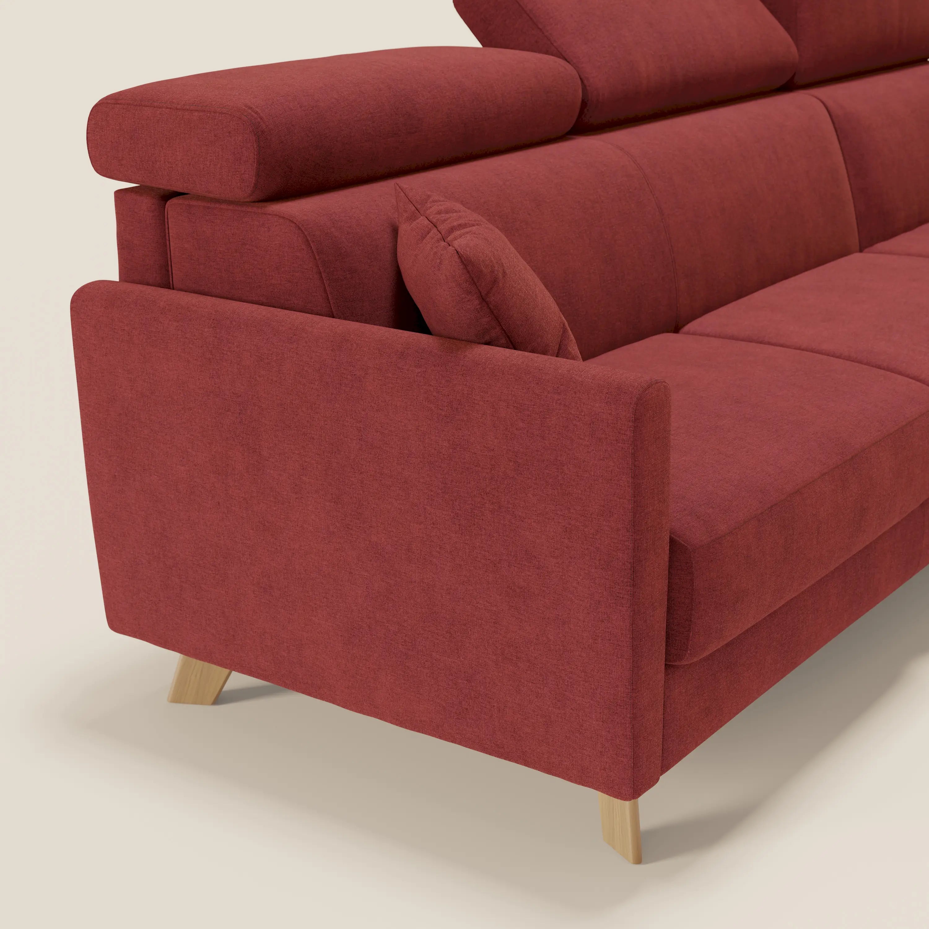 Primo piano del divano letto angolare sfoderabile Francy di Divani.Store in tessuto smacchiabile T17 rosso, con poggiatesta reclinabili, penisola contenitore, braccioli squadrati e gambe in legno chiaro. Lo Stile Nordico si staglia su uno sfondo beige.