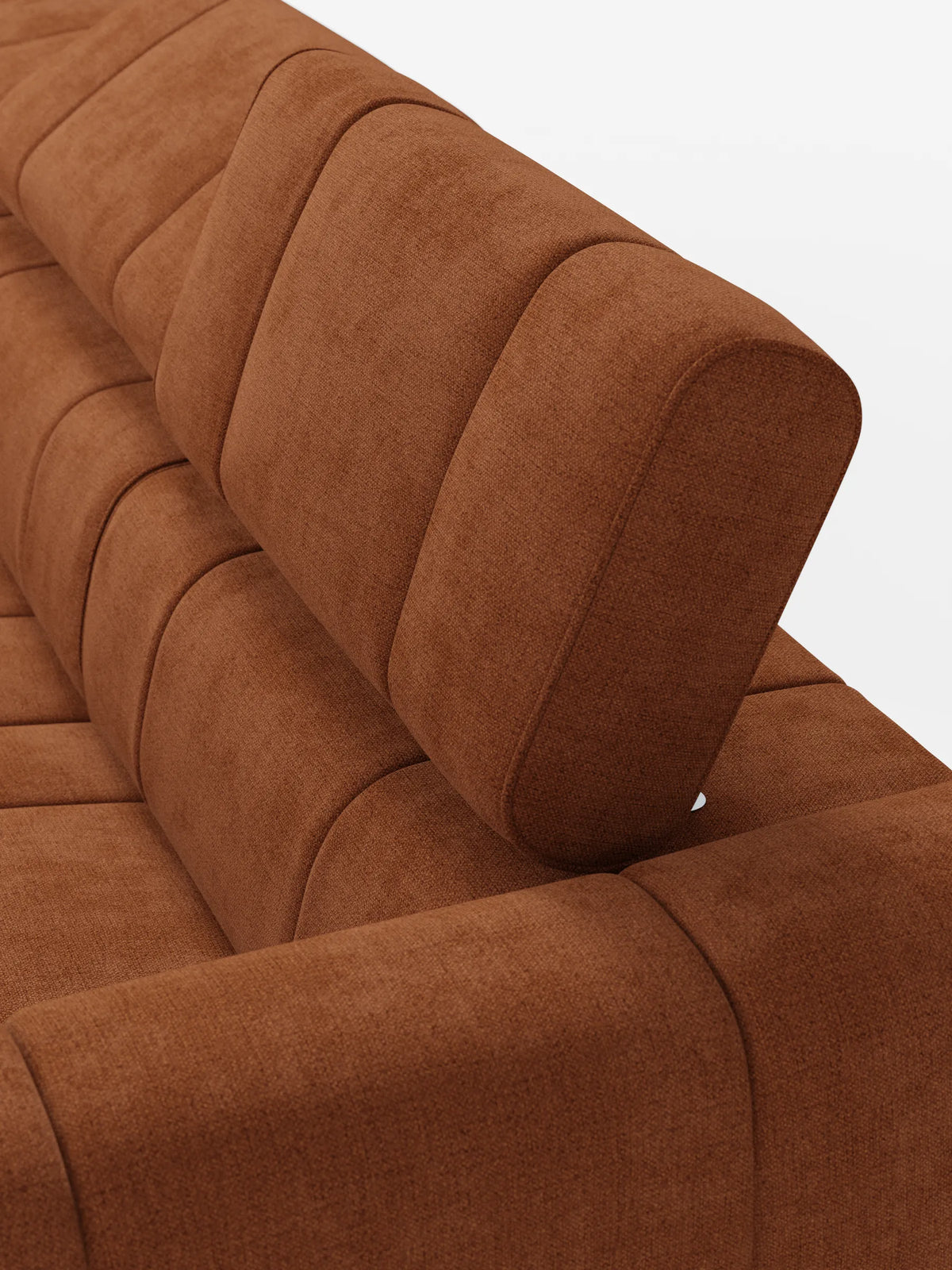 Un primo piano di un divano angolare modulare Giotto color ruggine, a 5 posti, lungo 296 cm, con penisola e funzione relax elettrica opzionale, rivestito in tessuto smacchiabile T23, caratterizzato da profonde cuciture verticali e da un poggiatesta regolabile, su uno sfondo chiaro a tinta unita.