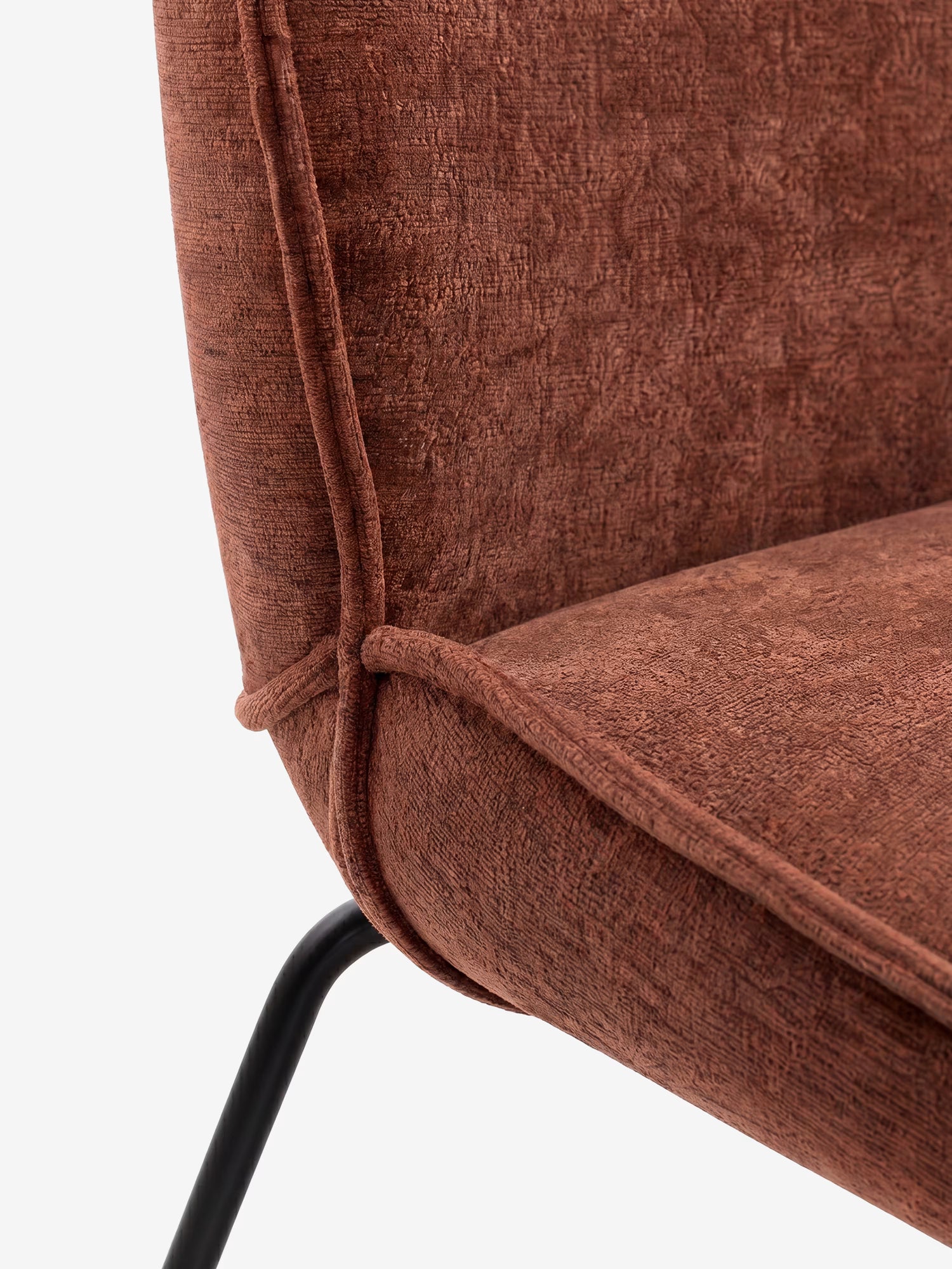 Primo piano di Iride, una sedia imbottita di Divani.Store, rivestita in morbido tessuto materico rosso-marrone. L'immagine mette in risalto il punto di giunzione tra seduta e schienale, con dettagli di bordatura e una gamba angolare in metallo nero.