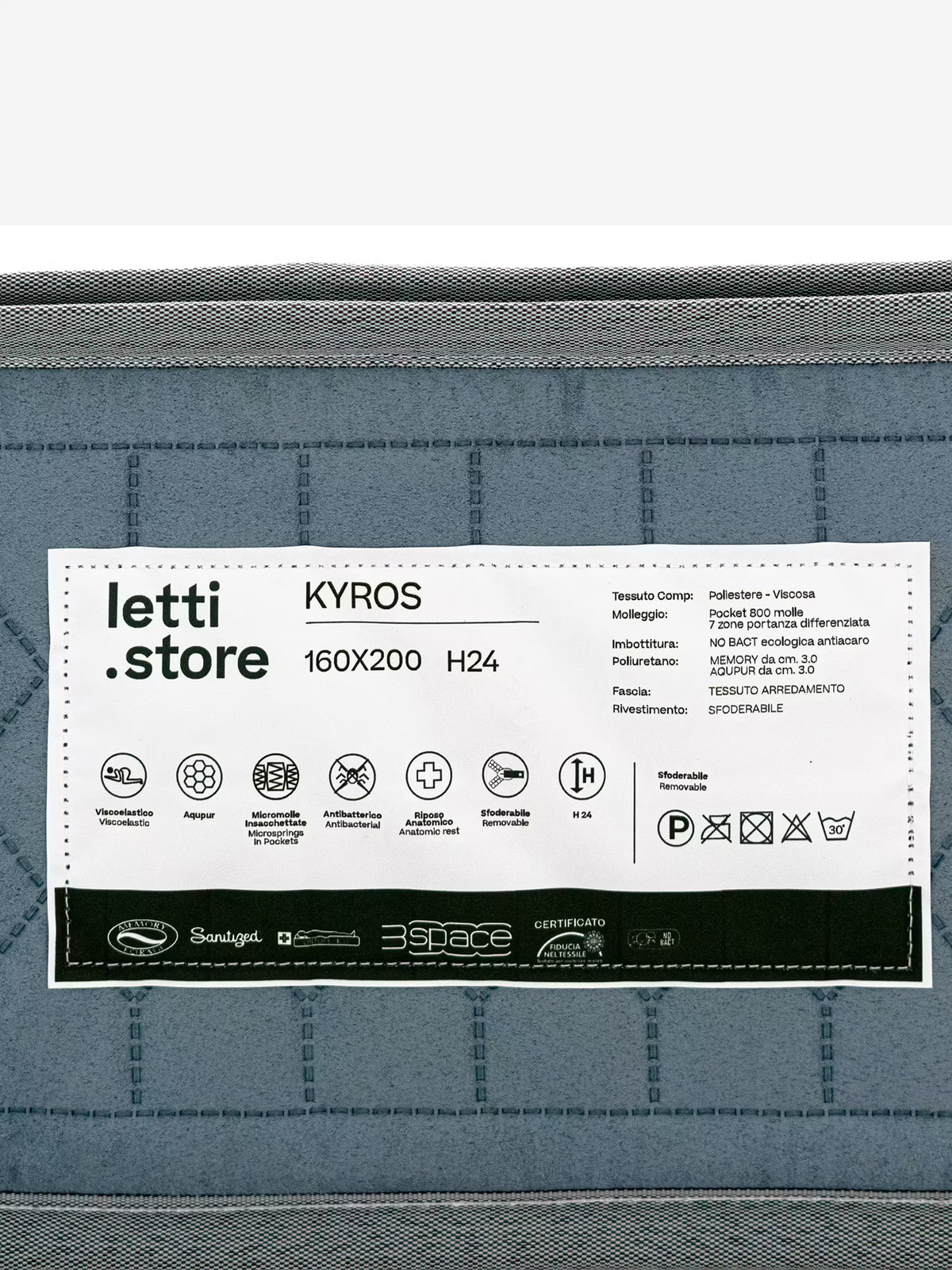 Un'etichetta bianca apposta su un materasso trapuntato grigio riporta la scritta “Divani.Store” e il nome del modello “KYROS – Materasso Luxury a molle insacchettate e memory con Supporto Posturale Intelligente a 7 Zone”, dalle dimensioni di 160x200 cm e con un’altezza di 24 cm. Sotto, alcune icone indicano caratteristiche quali traspirabilità, materiali ipoallergenici e sostegno ortopedico. I simboli italiani di lavaggio e le informazioni sui materiali evidenziano l’uso di micro molle insacchettate e