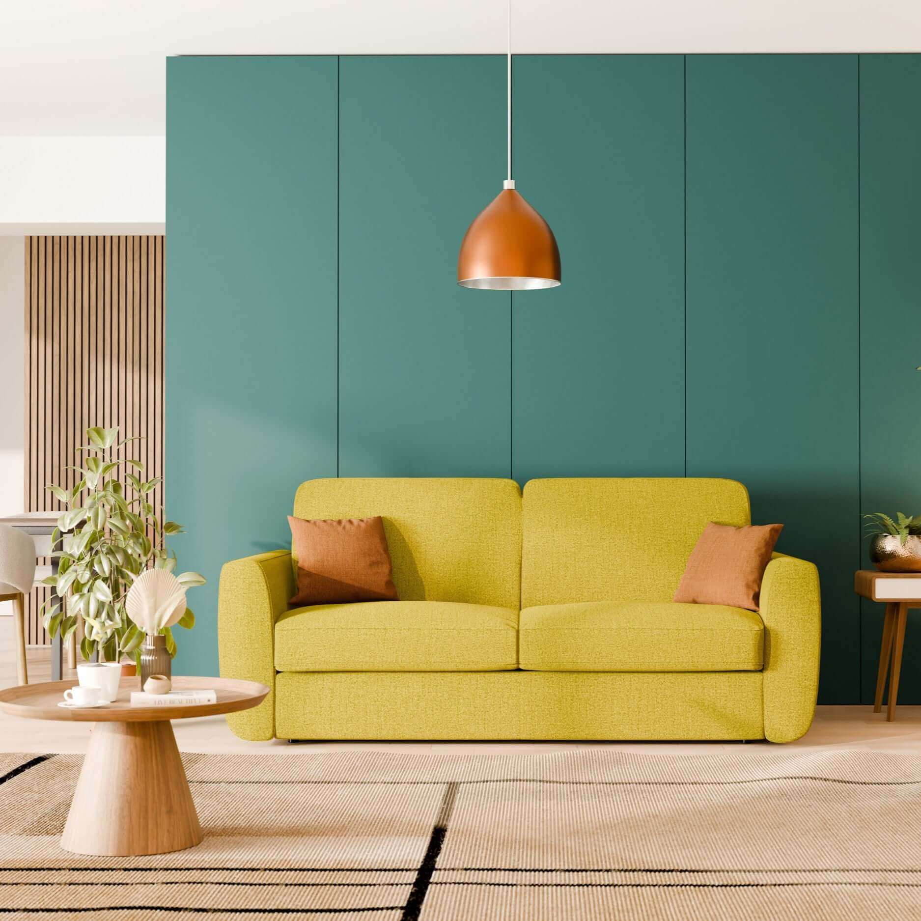Un soggiorno moderno con il divano letto sfoderabile Leonida con materasso H18 cm in tessuto Smacchiabile T23 giallo sole di Divani.Store, due cuscini marroni, una parete d'accento a pannelli verdi, una luce a sospensione in rame, piante e un arredamento minimalista.