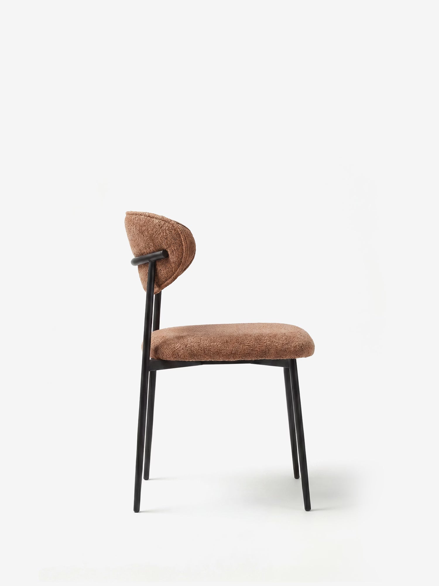 La sedia Luce, imbottita in morbido tessuto ciniglia, di Divani.Store presenta uno schienale curvo imbottito, una morbida seduta marrone, sottili gambe in metallo nero e un profilo minimalista che risalta su uno sfondo bianco.