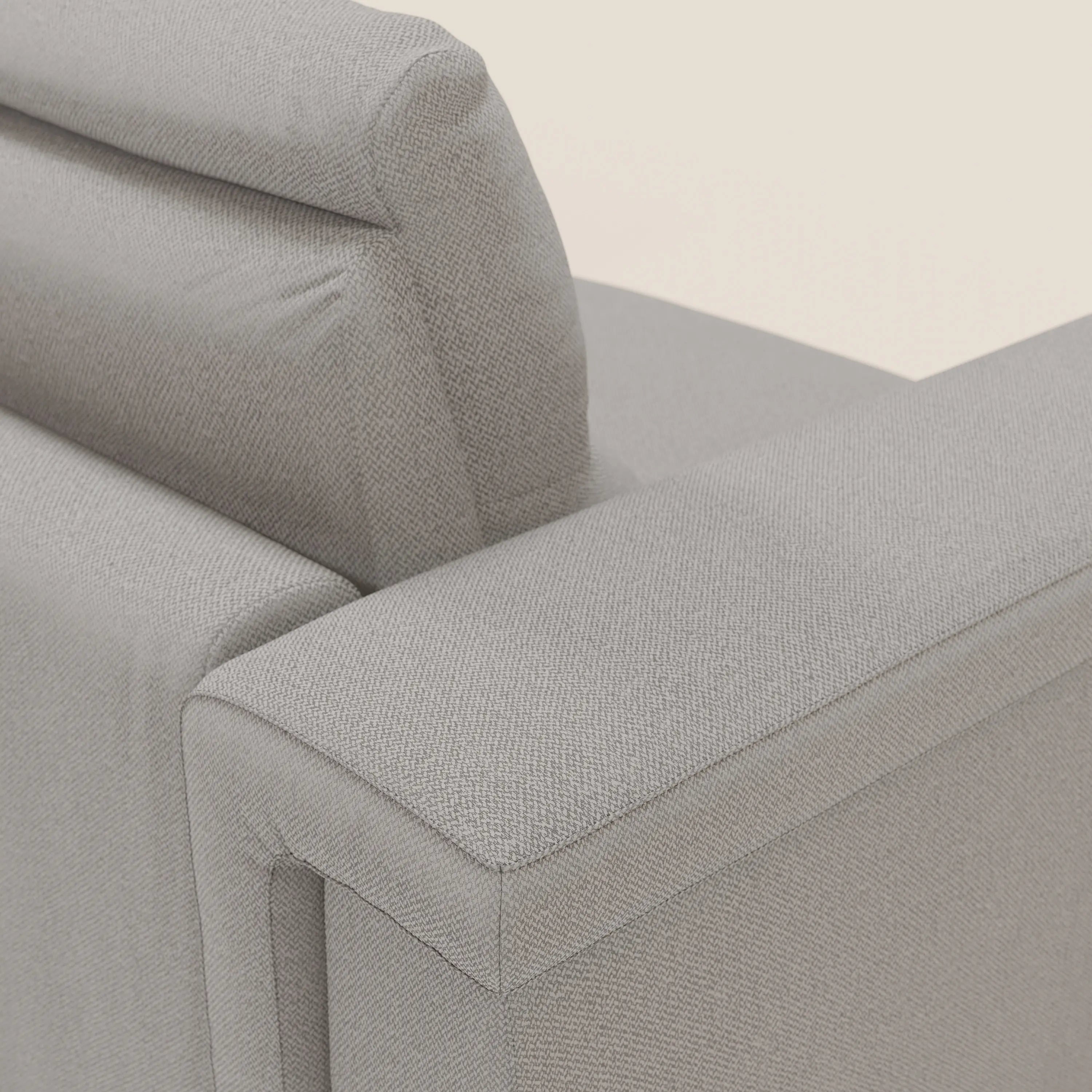 Primo piano del divano letto angolare Magnolia con penisola contenitore di Divani.Store in tessuto smacchiabile grigio T05, che mostra l'ampio bracciolo che incontra lo schienale imbottito, con cuciture curate e una trama sottile.