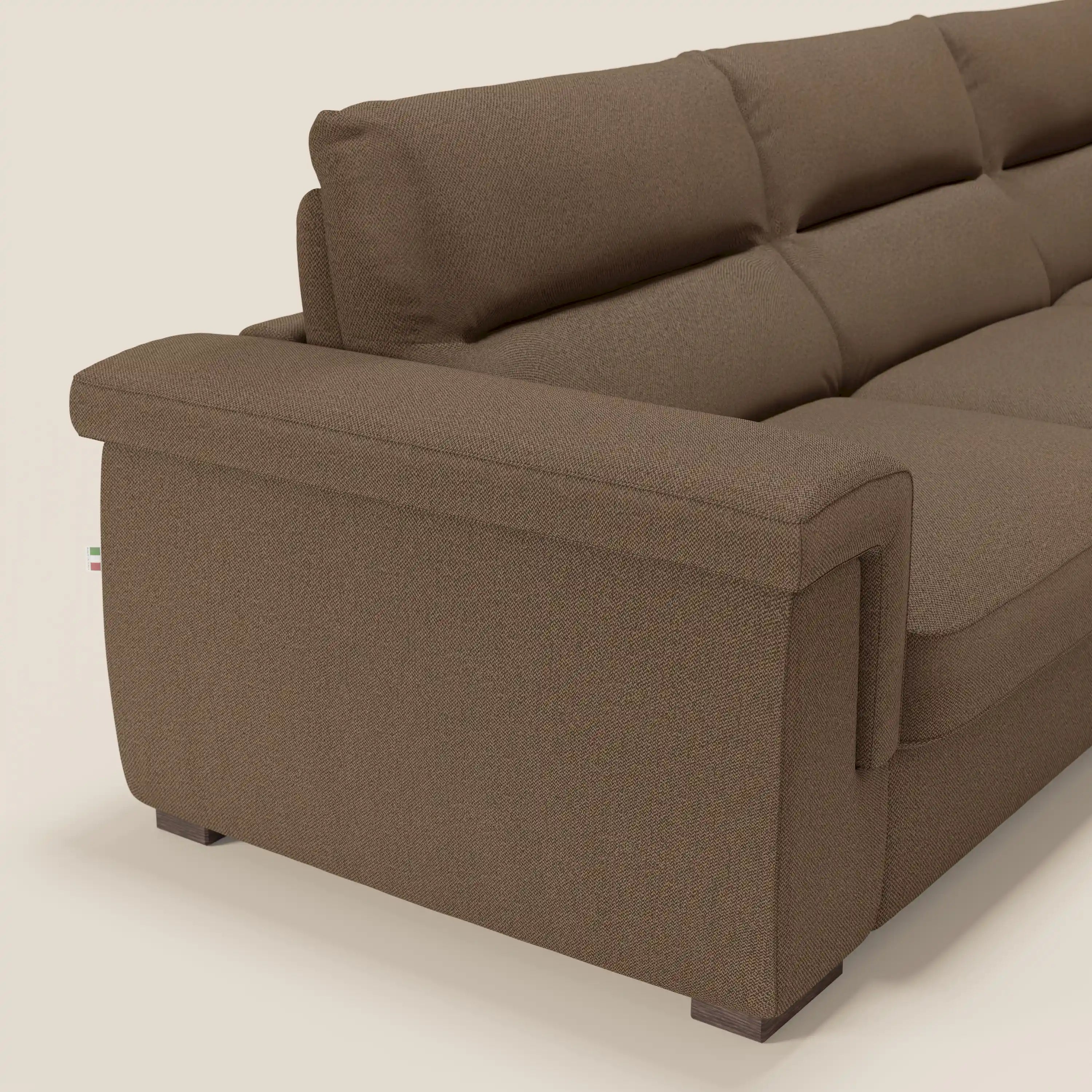 Primo piano del divano letto angolare Magnolia con penisola contenitore di Divani.Store, in tessuto smacchiabile T05 marrone, con ampi braccioli e cuscini di schienale in feltro, su sfondo beige.
