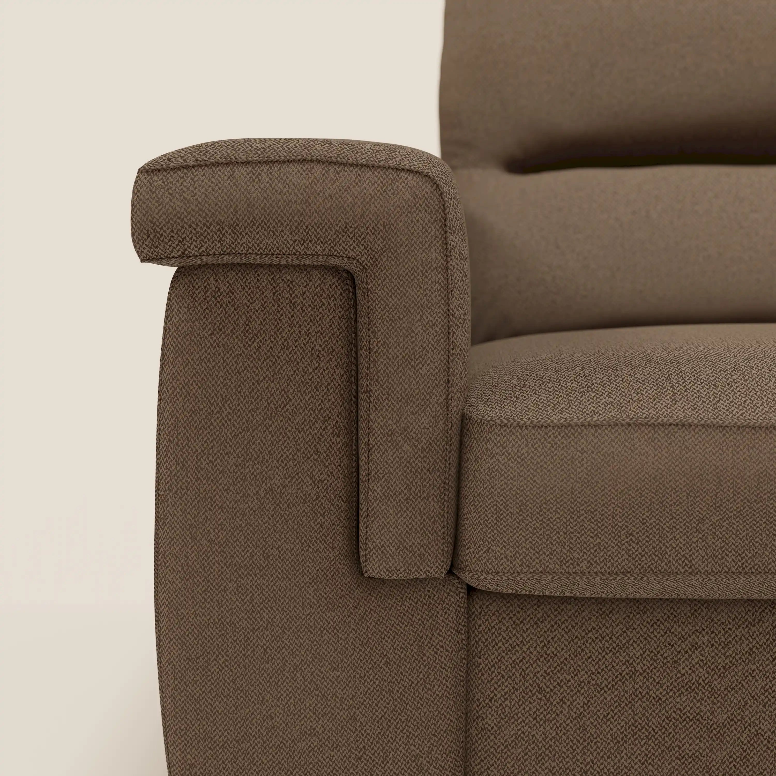 Primo piano del bracciolo sinistro e della seduta del divano letto angolare Magnolia con Penisola Contenitore di Divani.Store in smacchiabile T05 marrone, caratterizzato da braccioli arrotondati e cuscini spessi su uno sfondo chiaro.