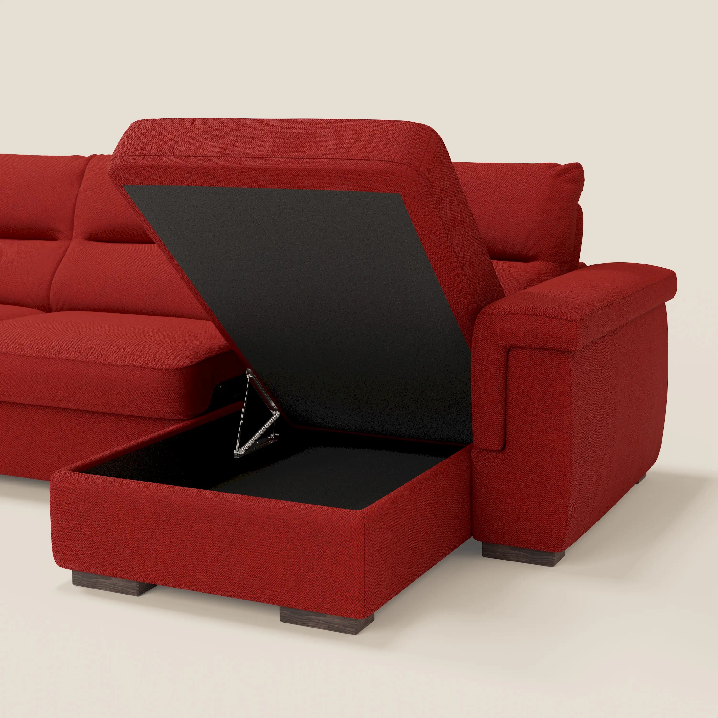 Il divano letto angolare Magnolia con Penisola Contenitore di Divani.Store è caratterizzato da tessuto T05 rosso antimacchia, cuscini trapuntati, ampi braccioli, gambe corte in legno scuro e uno spazioso vano portaoggetti foderato di nero sotto la poltrona sollevabile.