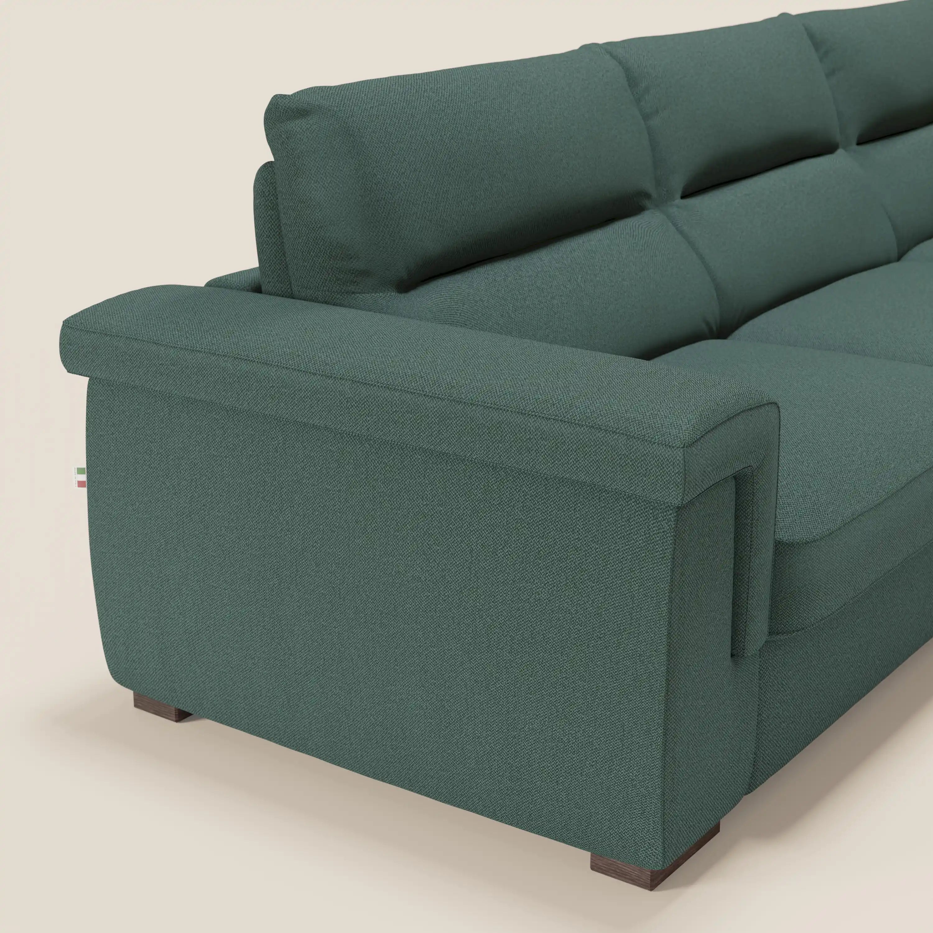 Primo piano dello schienale e del bracciolo del divano letto angolare Magnolia con Penisola Contenitore di Divani.Store in tessuto antimacchia T05 verde, con linee rette, piedini in legno e cuscini Comfort Profondo su uno sfondo chiaro.
