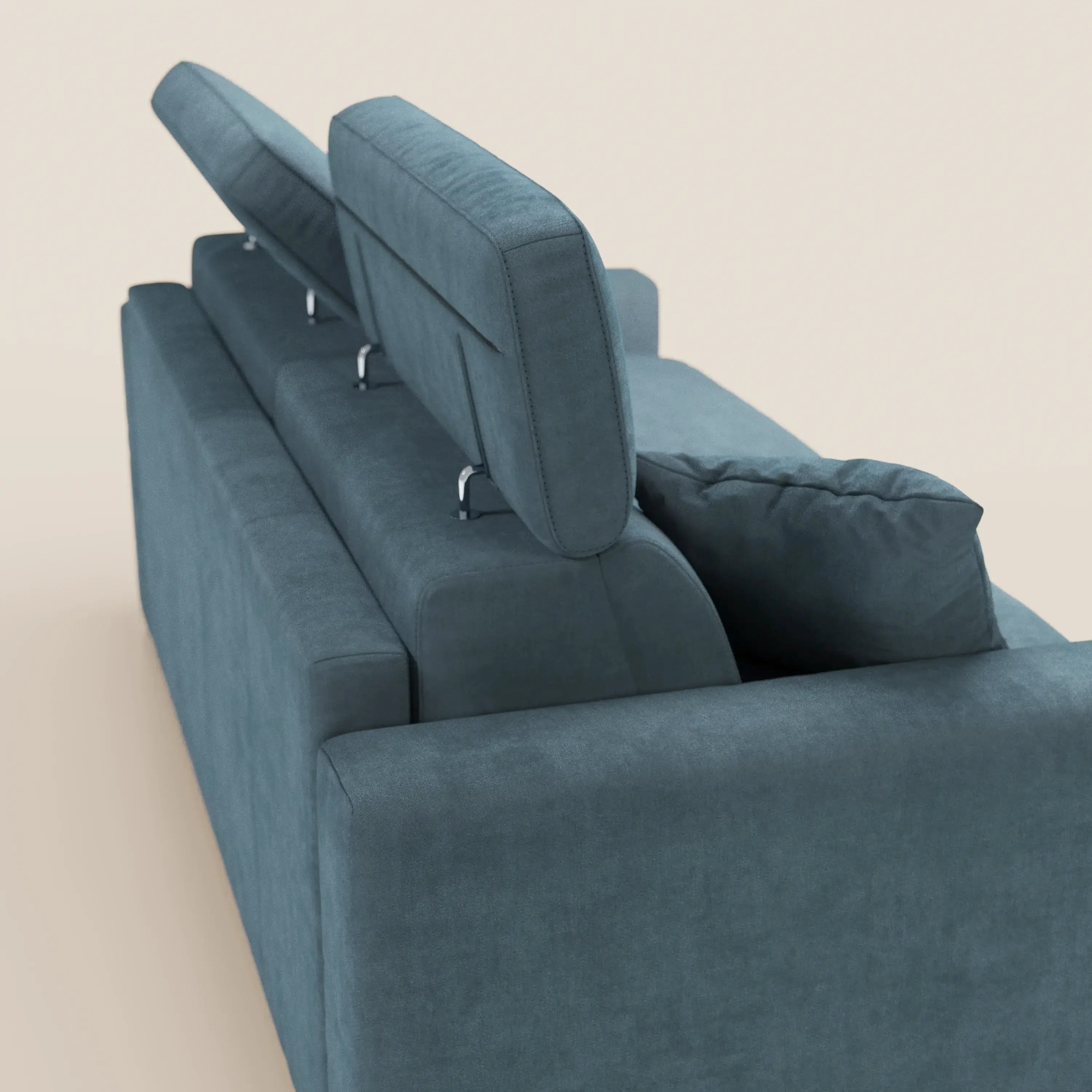 Il divano letto a 3 posti Maximus con materasso ALTO 20 cm di Divani.Store, in velluto blu, è dotato di due poggiatesta reclinabili, uno rialzato e uno abbassato, e di un cuscino coordinato sul bracciolo destro, il tutto su uno sfondo bianco sporco.