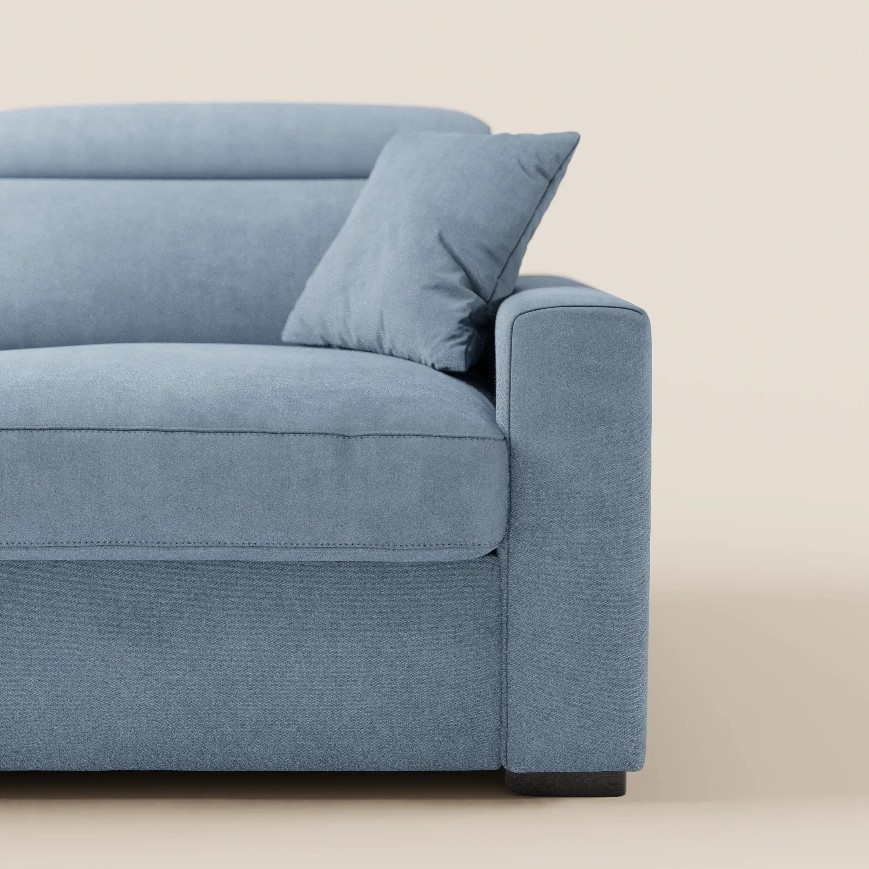 Un primo piano del divano letto a 3 posti Maximus di Divani.Store, realizzato in tessuto azzurro resistente alle macchie certificato Oeko-Tex, con bracciolo destro, seduta, schienale, cuscino coordinato e materasso alto 20 cm. Lo sfondo beige ne esalta le linee moderne e la morbidezza.
