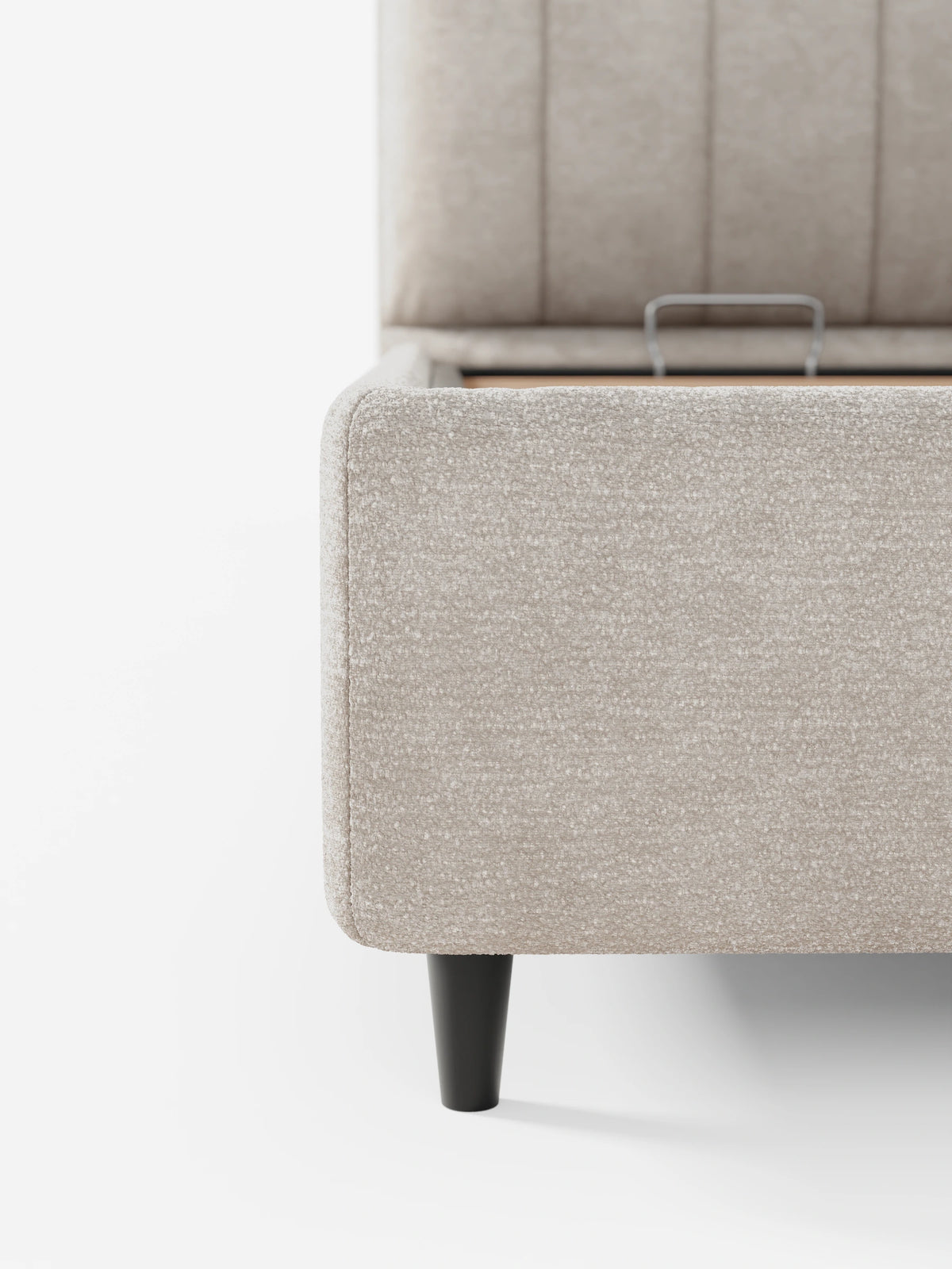Una vista angolare del letto imbottito ONYX con contenitore e testiera verticale in tessuto certificato Oeko-Tex®, caratterizzato da una testiera beige con cuciture verticali, una base rivestita in tessuto, gambe affusolate scure e una maniglia interna in metallo per l’apertura del contenitore.
