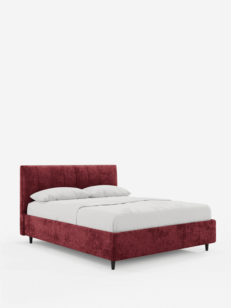 Letto imbottito ONYX con contenitore e testiera verticale in tessuto certificato Oeko-Tex® color rosso intenso con effetto testurizzato, caratterizzato da un’alta testiera a pannelli verticali, biancheria da letto bianca e quattro gambe scure affusolate su sfondo bianco.