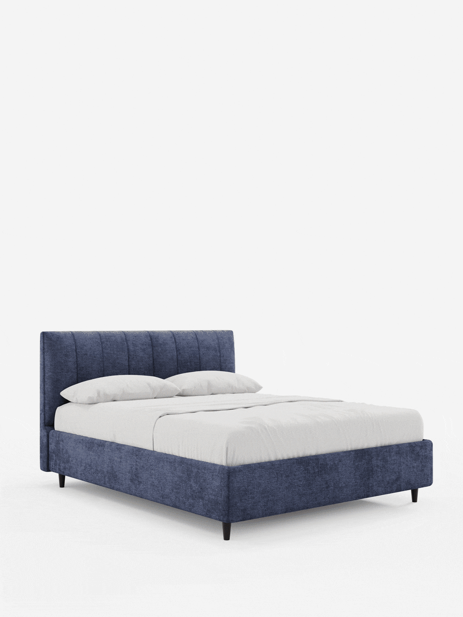 Letto imbottito ONYX con contenitore e testiera verticale in tessuto certificato Oeko-Tex® blu scuro con effetto testurizzato, caratterizzato da un’alta testiera trapuntata verticalmente, sottili gambe nere e biancheria da letto di un bianco brillante.