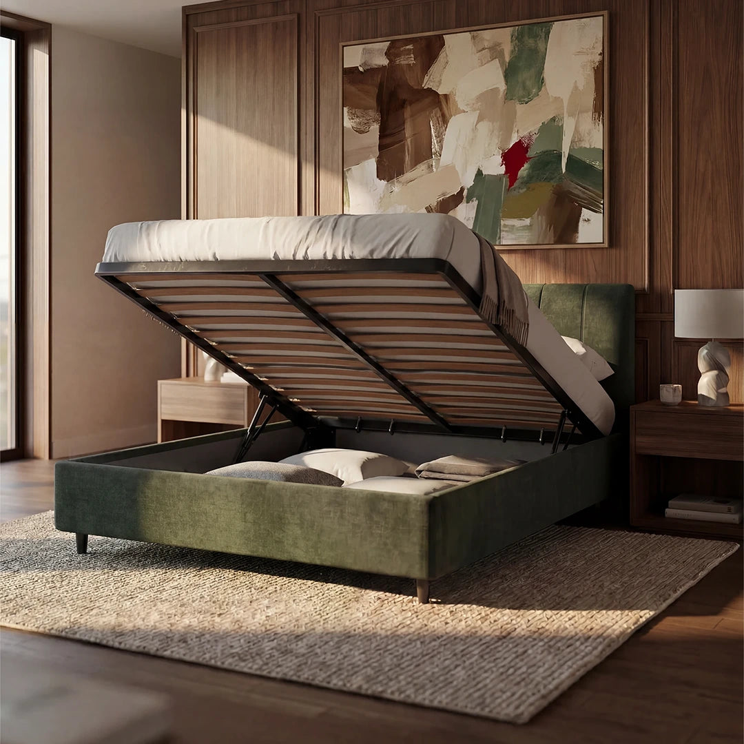 Una camera da letto moderna mette in risalto il letto imbottito ONYX con vano contenitore e testiera verticale in tessuto certificato Oeko-Tex® di Letti.store, con il materasso sollevato per consentire lo stoccaggio e i cuscini riposti al suo interno. Pareti in legno, opere d’arte astratta, comodini con lampade e luce naturale completano l’ambiente.