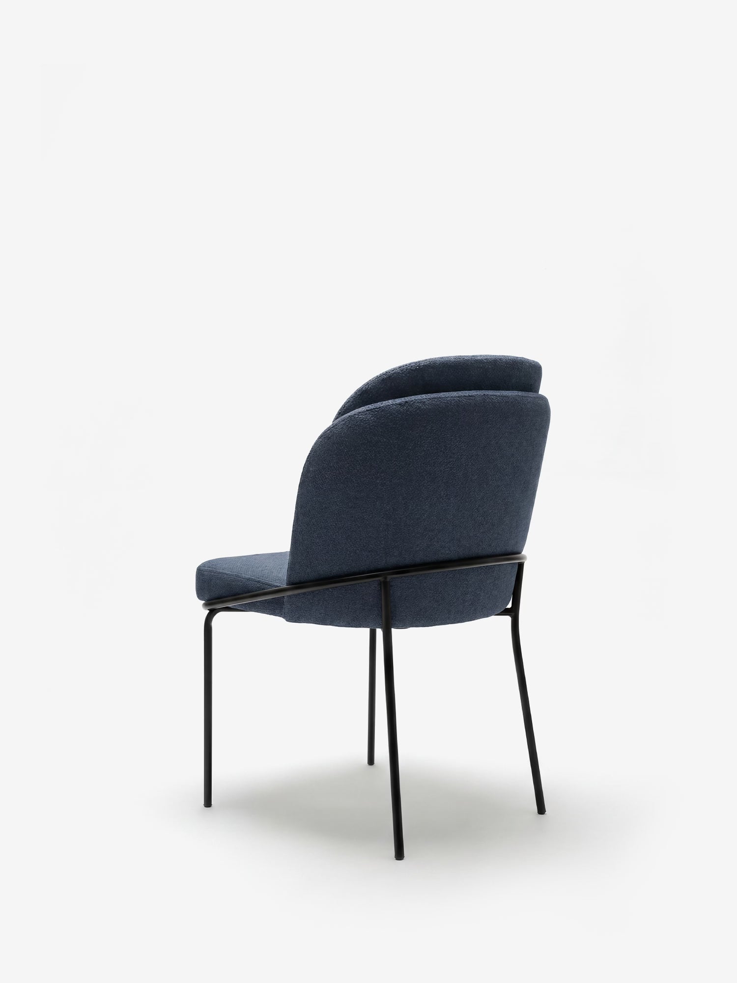 La sedia Plissè di Divani.Store è rivestita in tessuto impermeabile blu scuro, con schienale plissettato e gambe sottili in metallo nero. Dal design moderno ed elegante, offre comfort grazie alle linee curve su sfondo bianco.