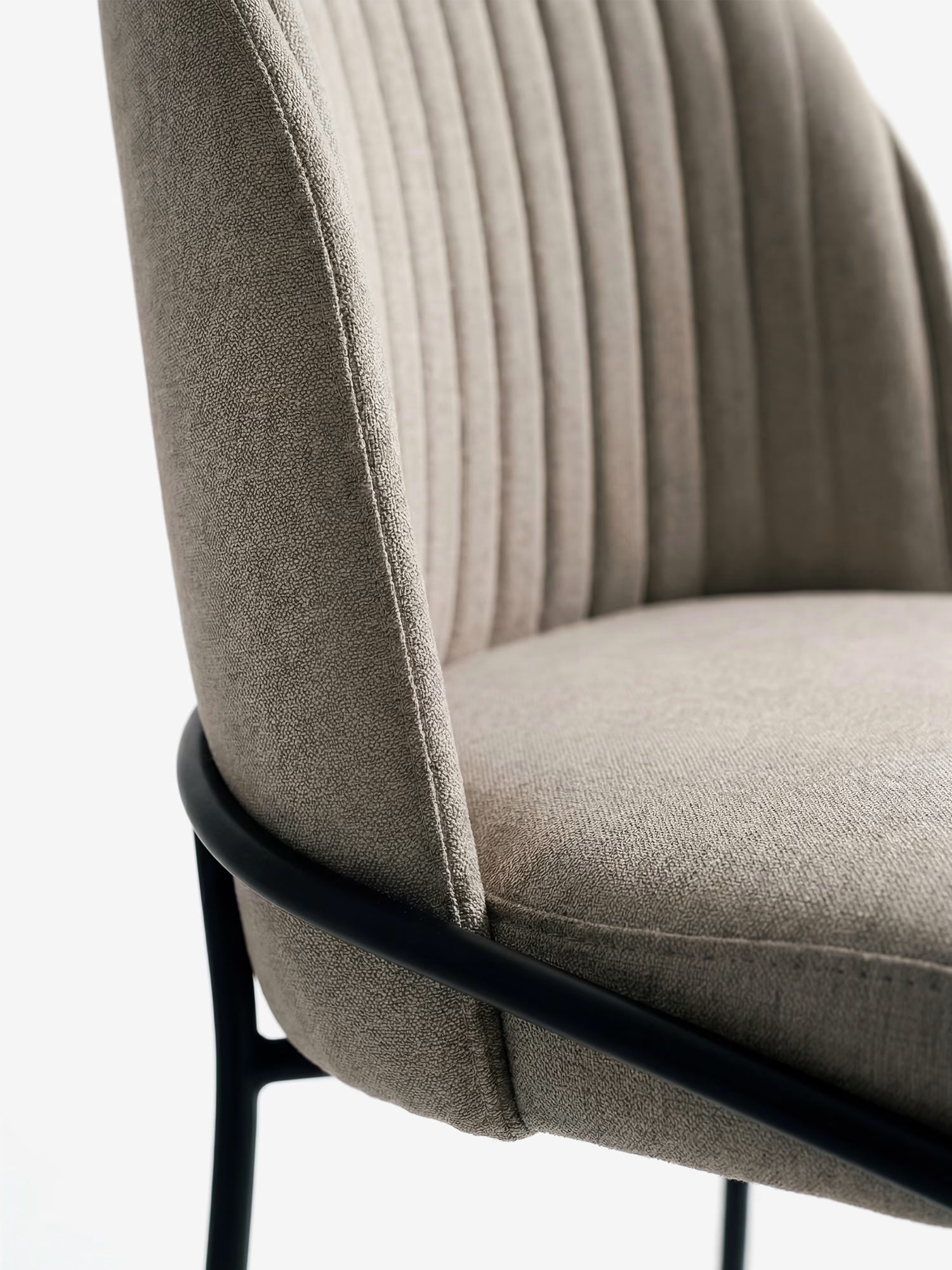 Primo piano della sedia imbottita Plissè in tessuto impermeabile di Divani.Store, caratterizzata da uno schienale plissettato, tessuto beige chiaro ed eleganti gambe in metallo nero che le conferiscono un look moderno.