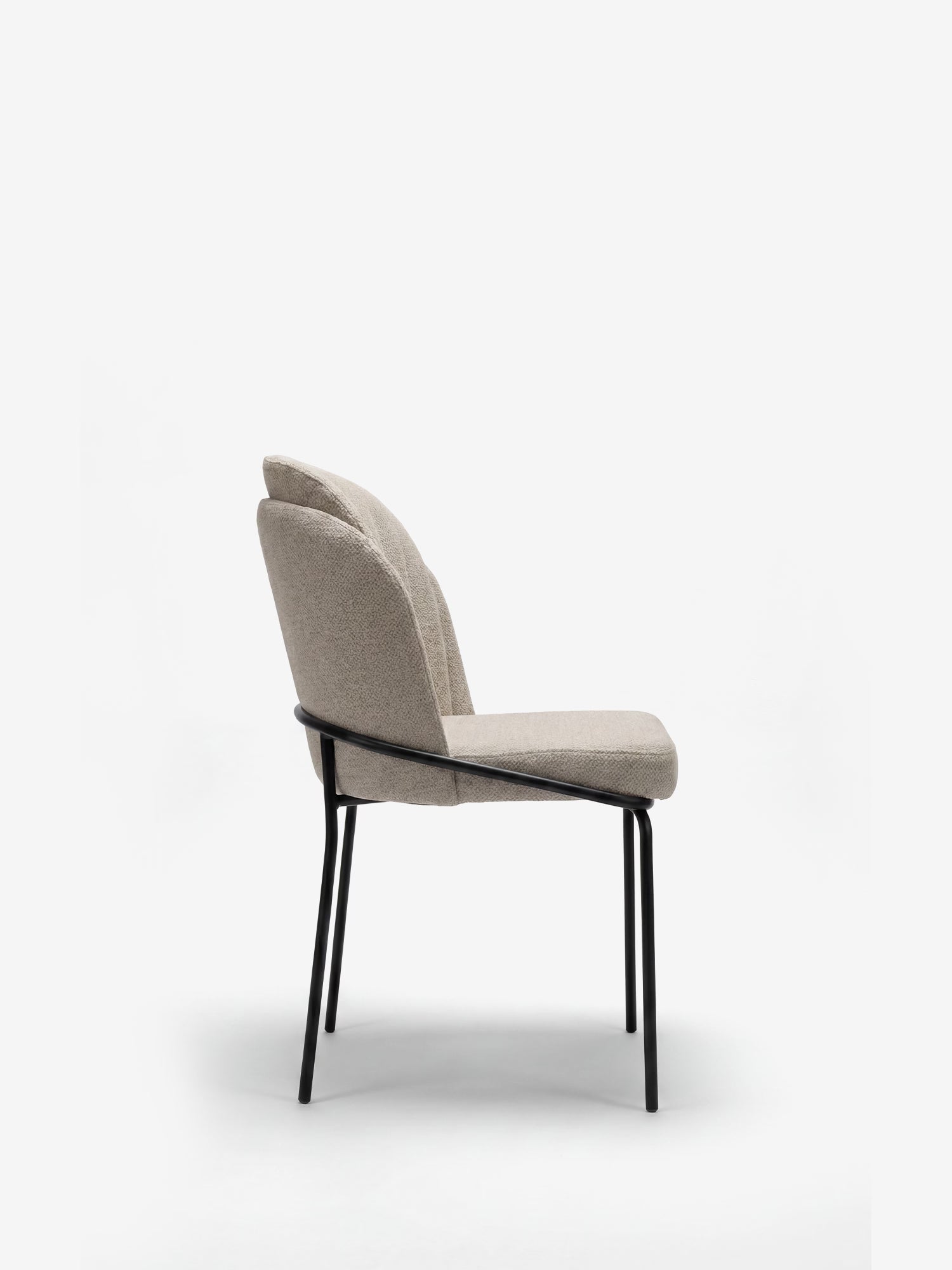 La sedia imbottita Plissè di Divani.Store è realizzata in tessuto impermeabile beige chiaro, presenta uno schienale plissettato, una seduta imbottita ed eleganti gambe in metallo nero. Nella foto è raffigurata di profilo su uno sfondo bianco a tinta unita.