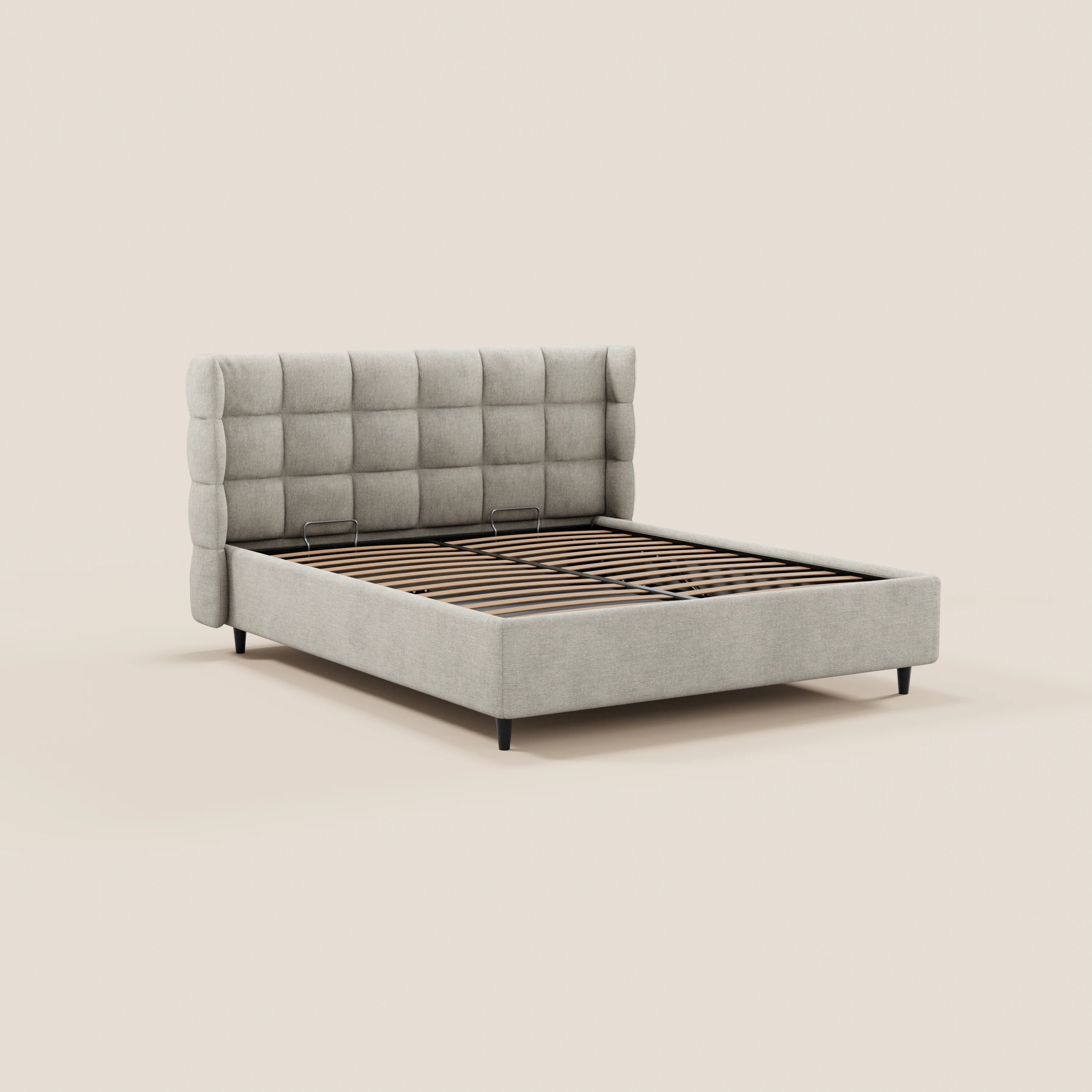 Il letto imbottito RAGNAR di Letti.store presenta una testiera alta e avvolgente con rivestimento capitonné in tessuto grigio chiaro certificato Oeko-Tex®, gambe angolate nere e doghe in legno a vista su sfondo beige. Design minimalista, raffigurato senza materasso.