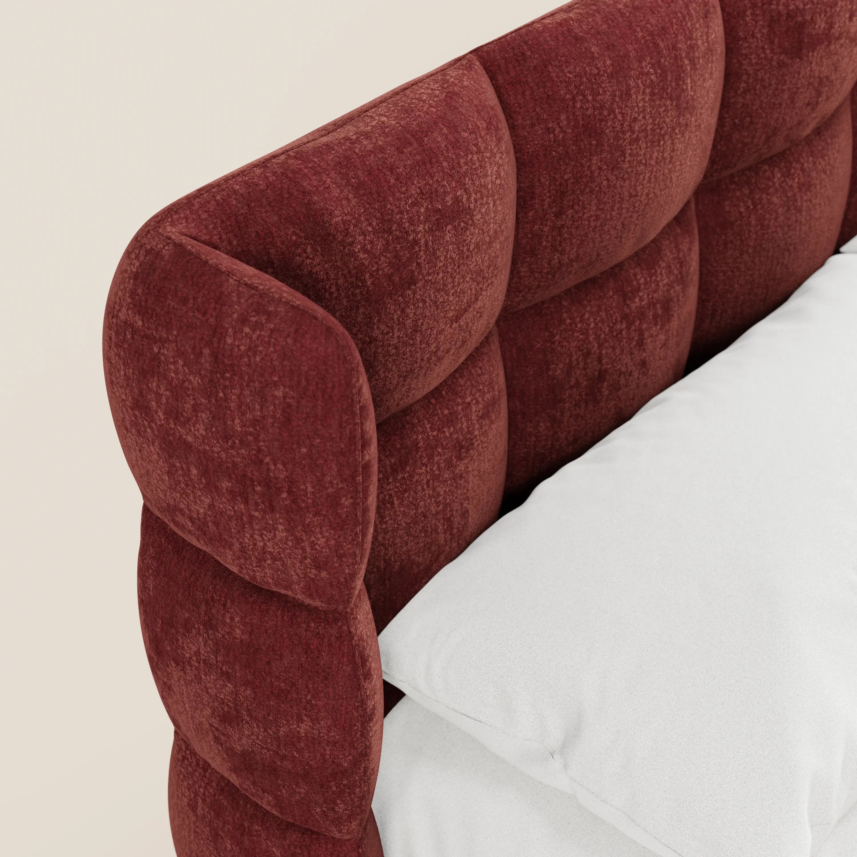 Primo piano del letto imbottito RAGNAR di Letti.store, caratterizzato da una morbida testiera capitonné trapuntata, realizzata in un elegante tessuto certificato Oeko-Tex®. Un cuscino bianco e la biancheria da letto sono appoggiati accanto alla testiera arrotondata e imbottita, dotata di vano portaoggetti.