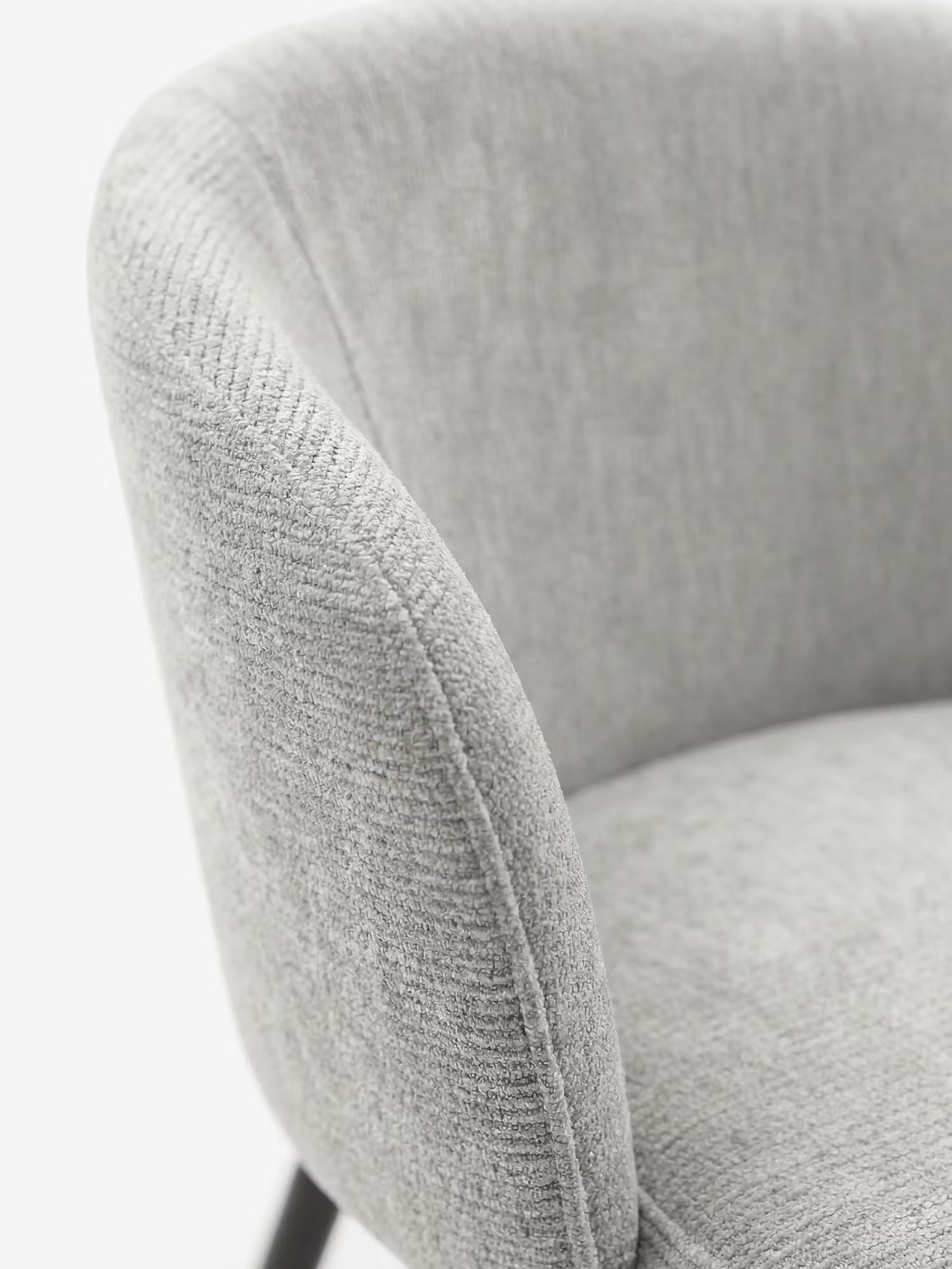 Primo piano della sedia Rovo con braccioli imbottita di Divani.Store, caratterizzata da uno schienale curvo in ciniglia e braccioli integrati, con rivestimento grigio chiaro testurizzato e gambe in metallo nero, su uno sfondo bianco a tinta unita.