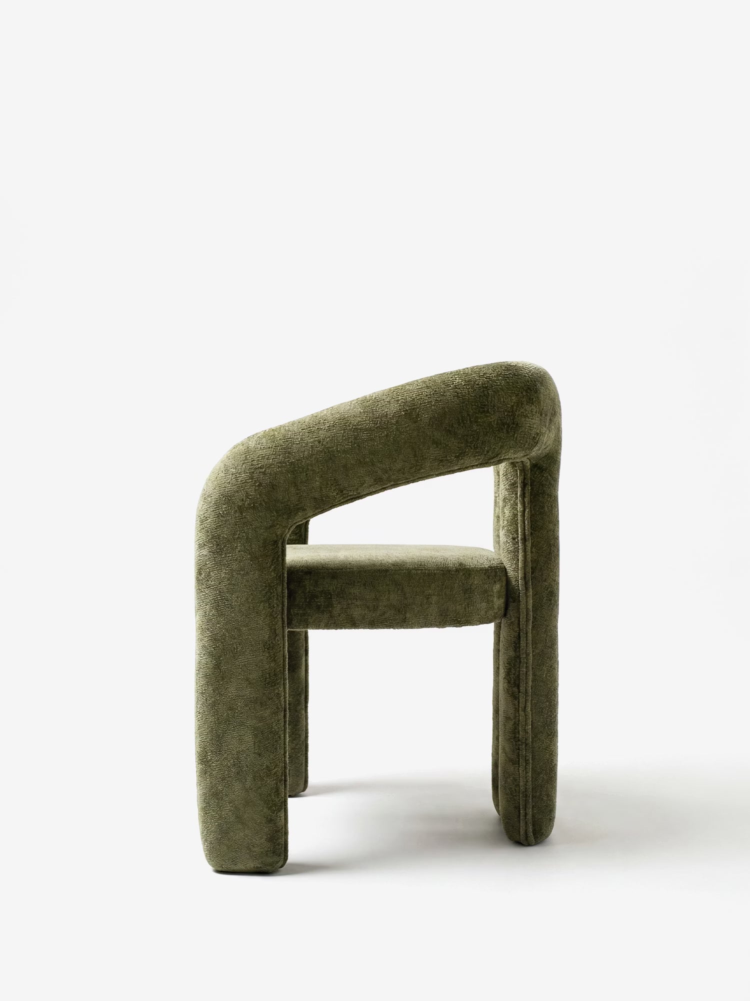 Vista laterale della sedia di design Sibilla di Divani.Store, interamente rivestita in ciniglia verde oliva, con gambe spesse e arrotondate e uno schienale curvo ad arco, raffigurata su uno sfondo bianco a tinta unita.