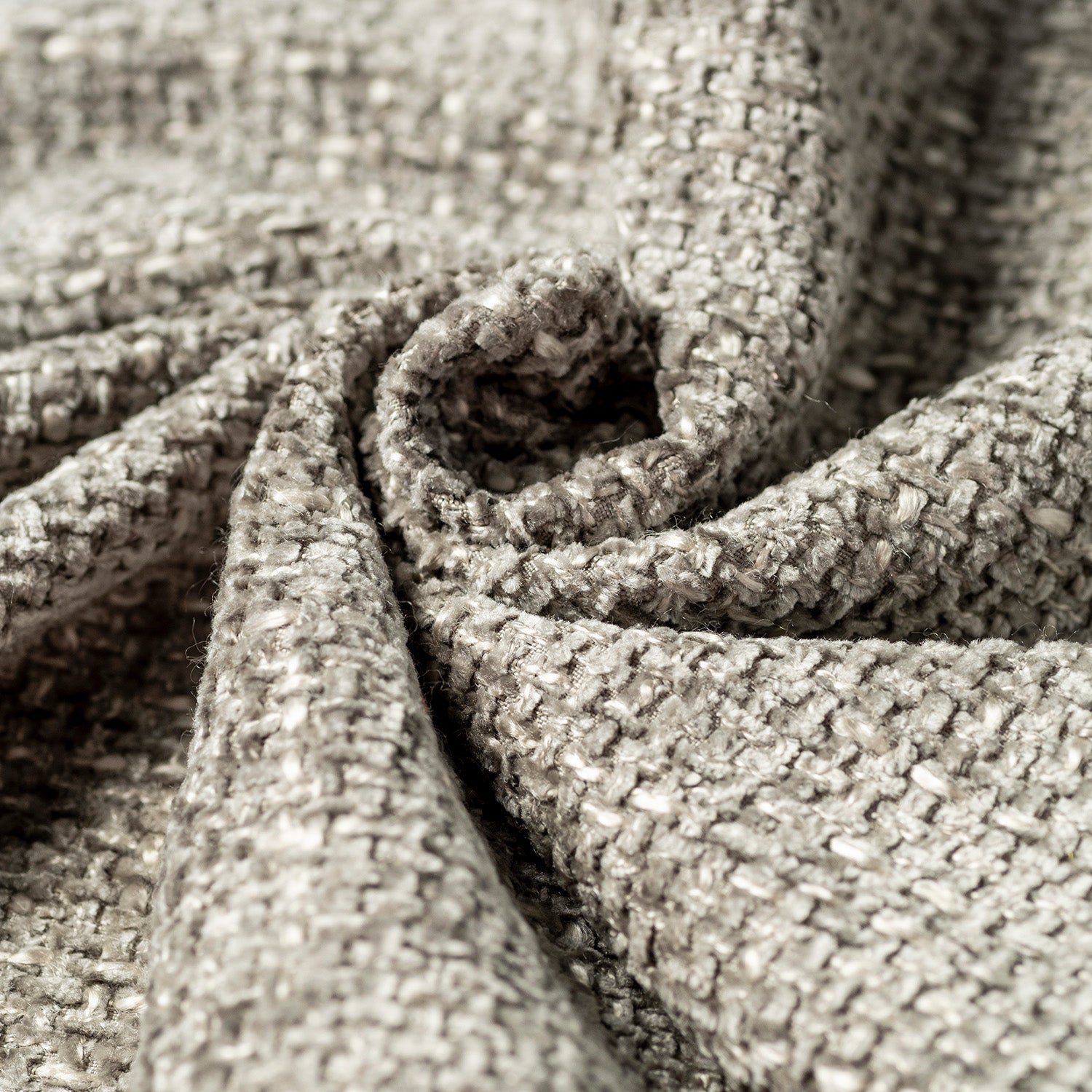 Primo piano del T10 Baobab di Divani.Store, un morbido tessuto a trama grossa in grigio chiaro con trattamento idrorepellente, certificazione Oeko-Tex e finitura smacchiabile. I fili visibili e le pieghe delicate creano ombre sottili.