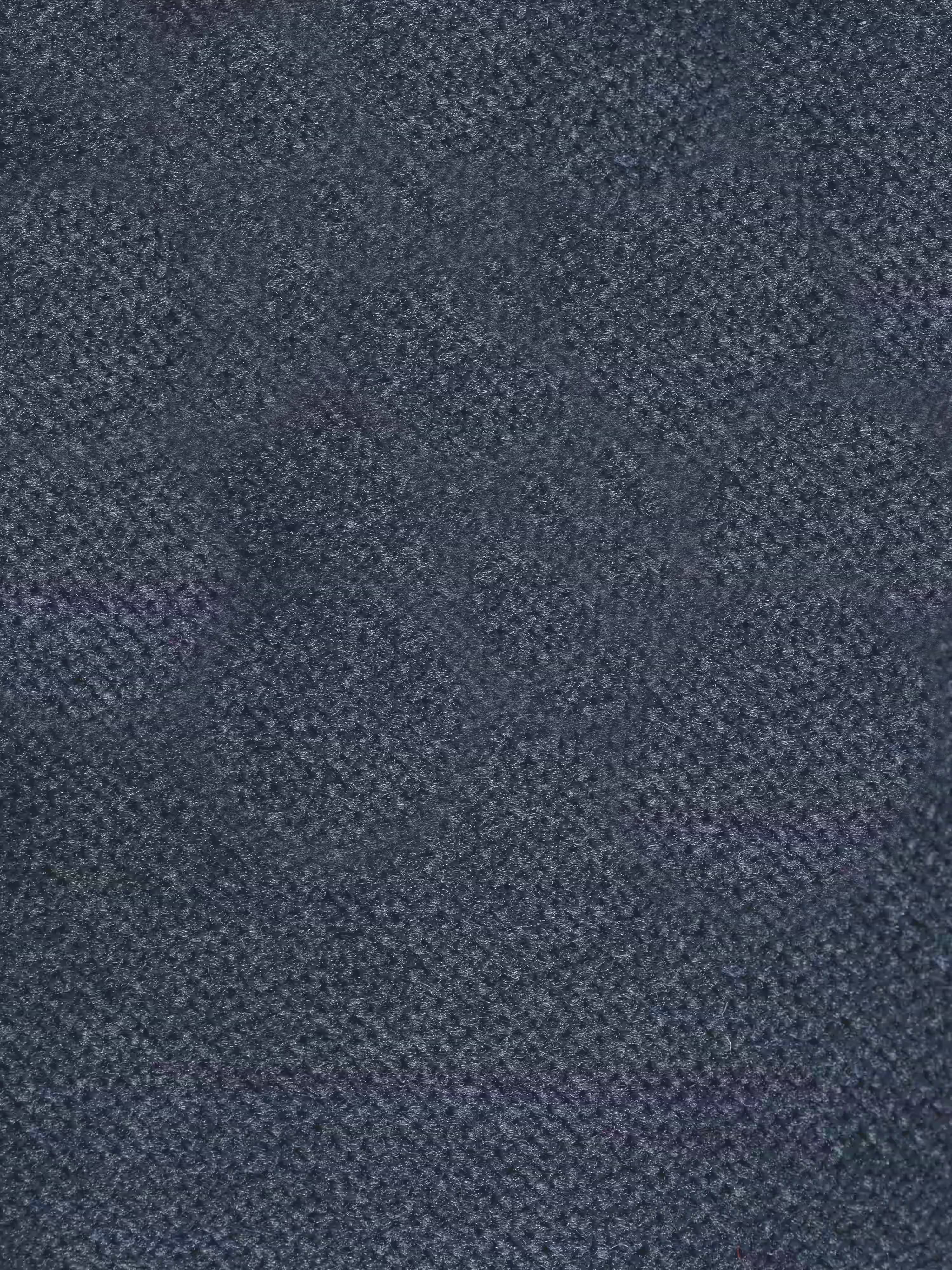 Primo piano dell’elegante “Michelangelo 4 Posti – Divano con 3 sedute estensibili e poggiatesta reclinabili” di Divani.Store, in blu scuro. Il tessuto smacchiabile in vellutino T30 presenta una delicata trama intrecciata con minuscoli puntini disposti in modo regolare, che ricordano la lana o il tweed. Tonalità di blu più chiare e più scure sono visibili su tutta la superficie, mettendo in risalto la sua finitura sofisticata, perfetta per valorizzare il tuo salotto.