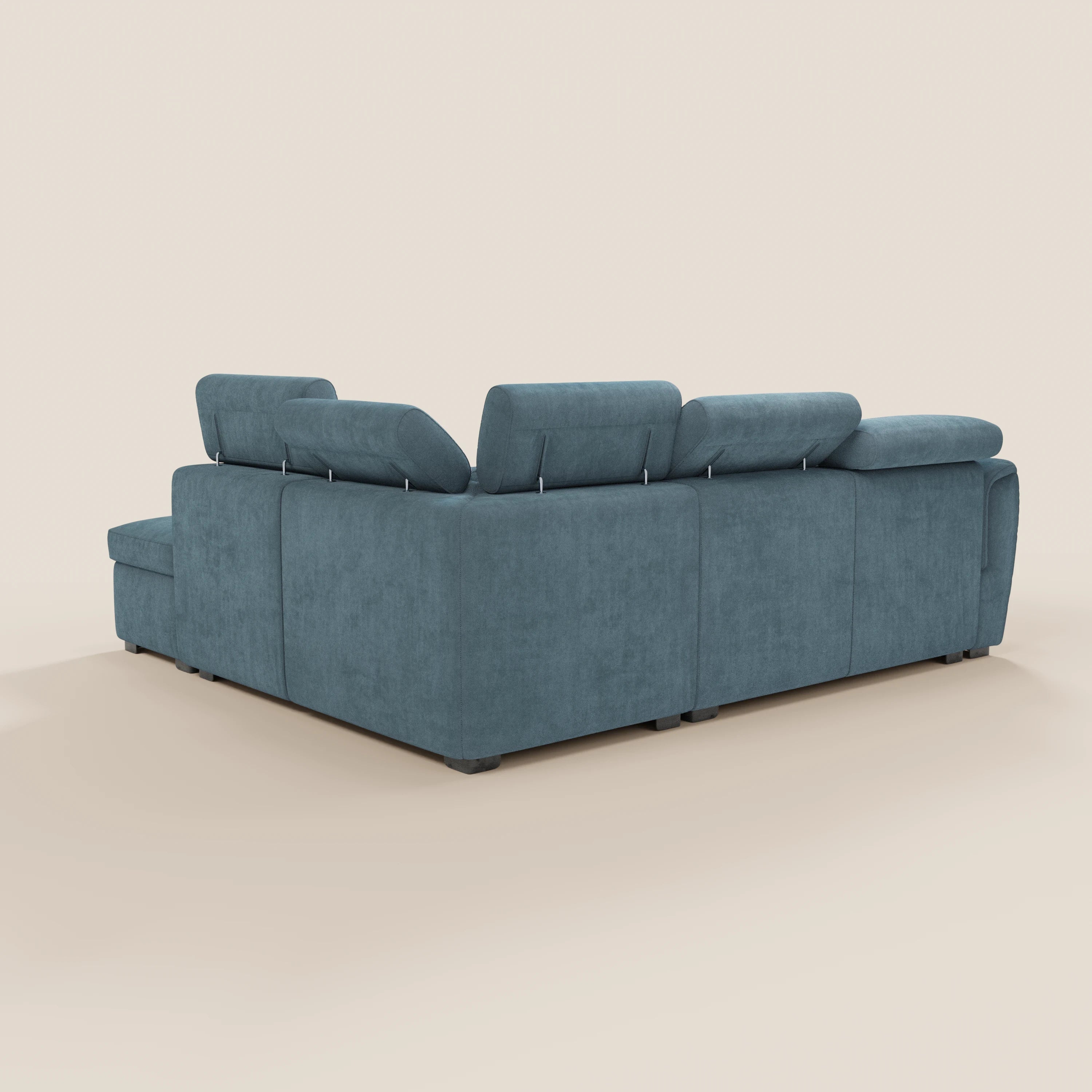Il divano angolare reversibile Titano di Divani.Store, ripreso di spalle da un’angolazione obliqua, è dotato di poggiatesta reclinabili, sedute ampie e un design moderno e lineare. Lo sfondo beige a tinta unita mette in risalto il suo audace tessuto blu certificato Oeko-Tex®.